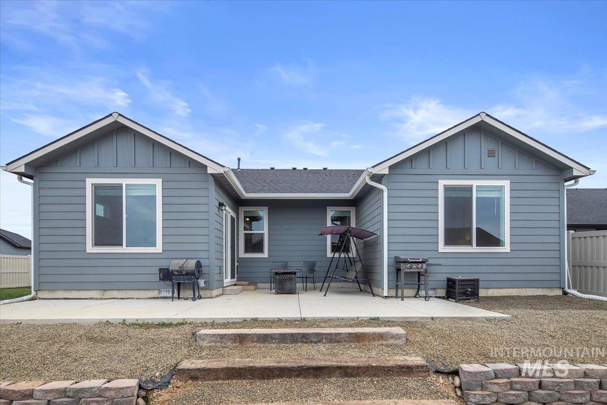 Rear view of property featuring a patio, board and batten siding, and roof with shingles
