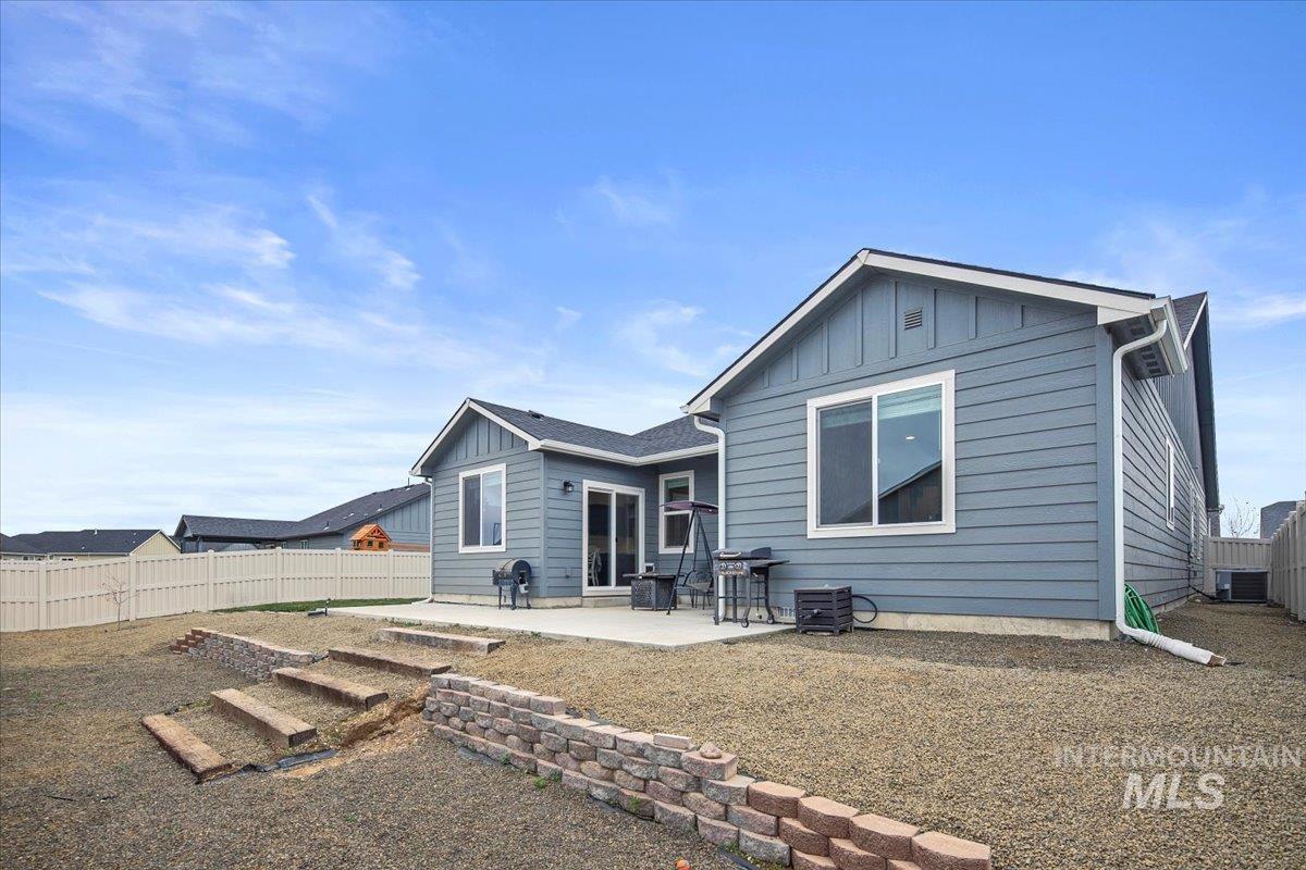 Rear view of property with board and batten siding, a patio, and a fenced backyard