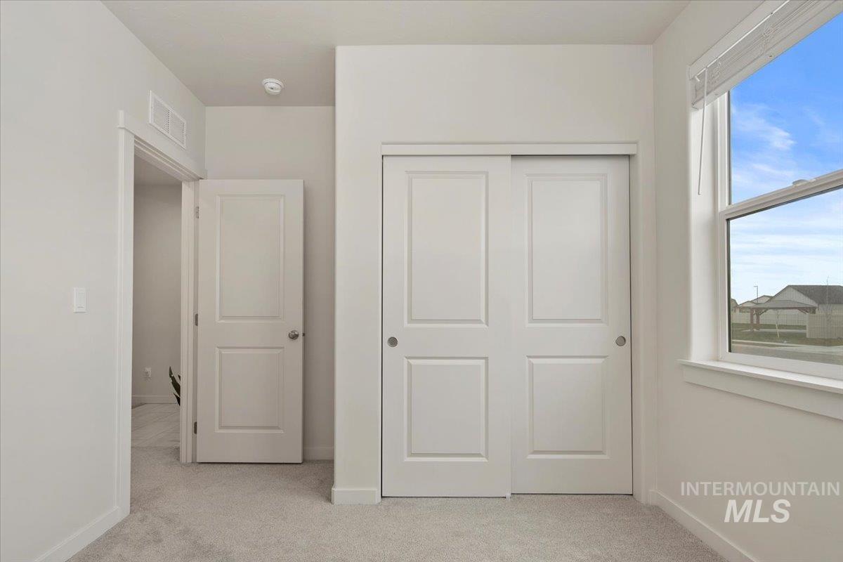 Unfurnished bedroom with light colored carpet and a closet
