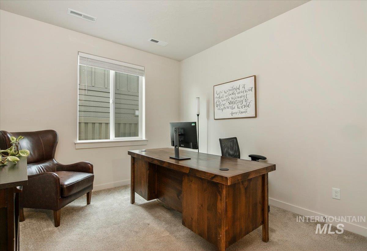 Home office with light colored carpet and baseboards