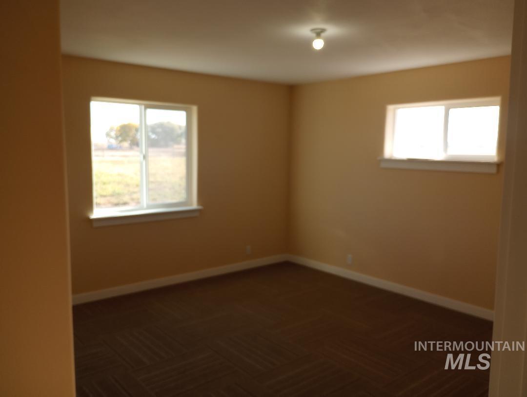 Spare room featuring baseboards and dark carpet