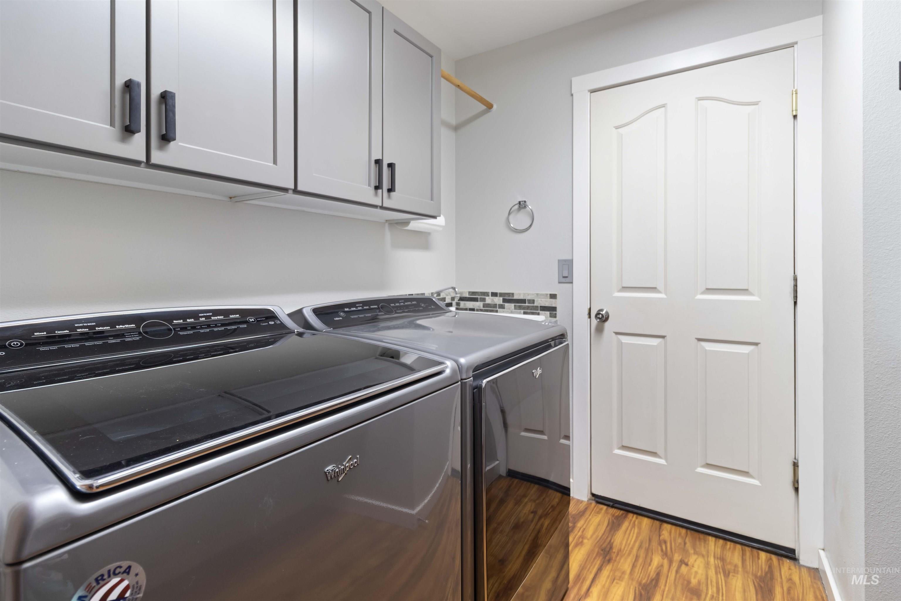 Washroom featuring dark wood finished floors, cabinet space, and independent washer and dryer