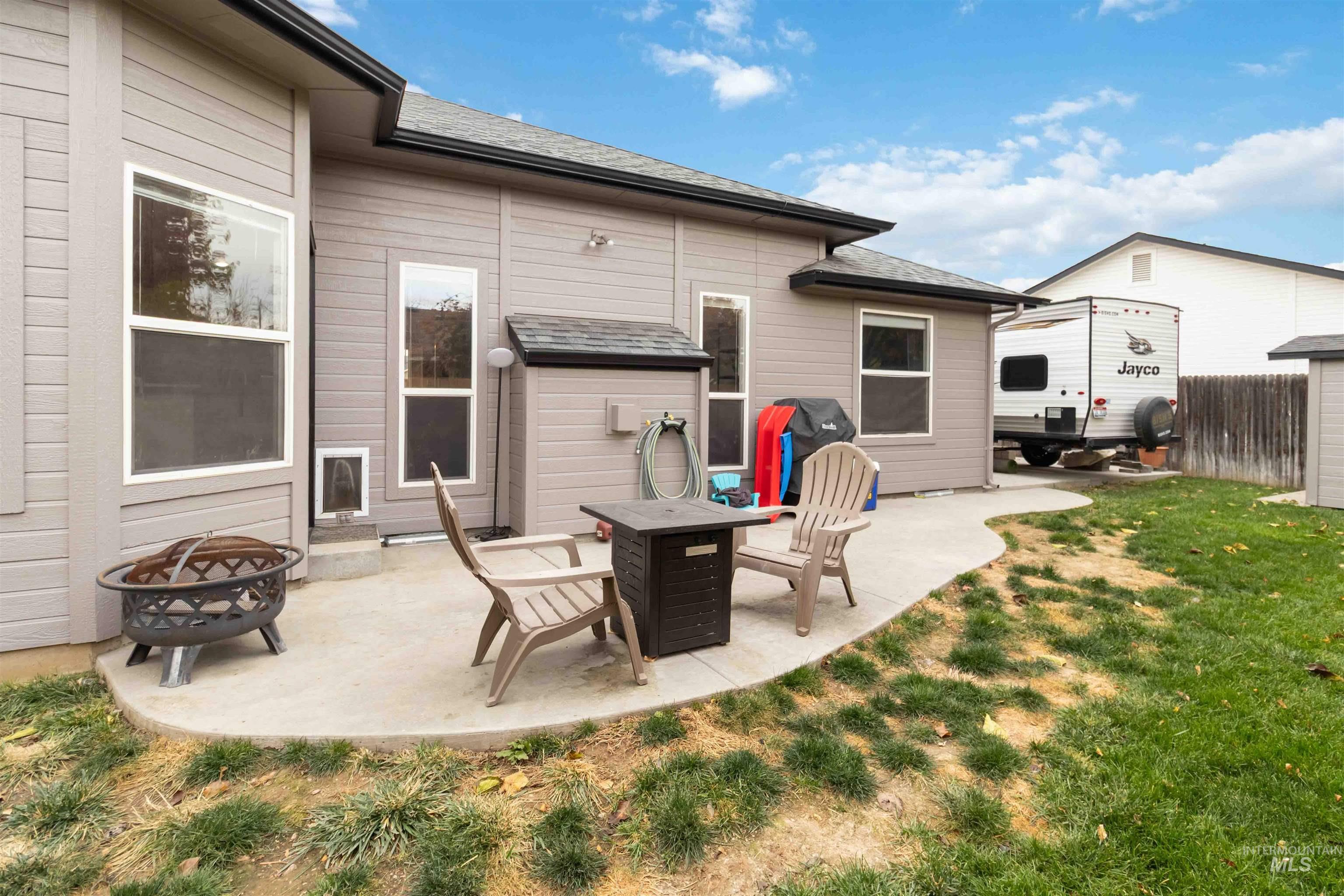 View of patio with an outdoor fire pit and a grill