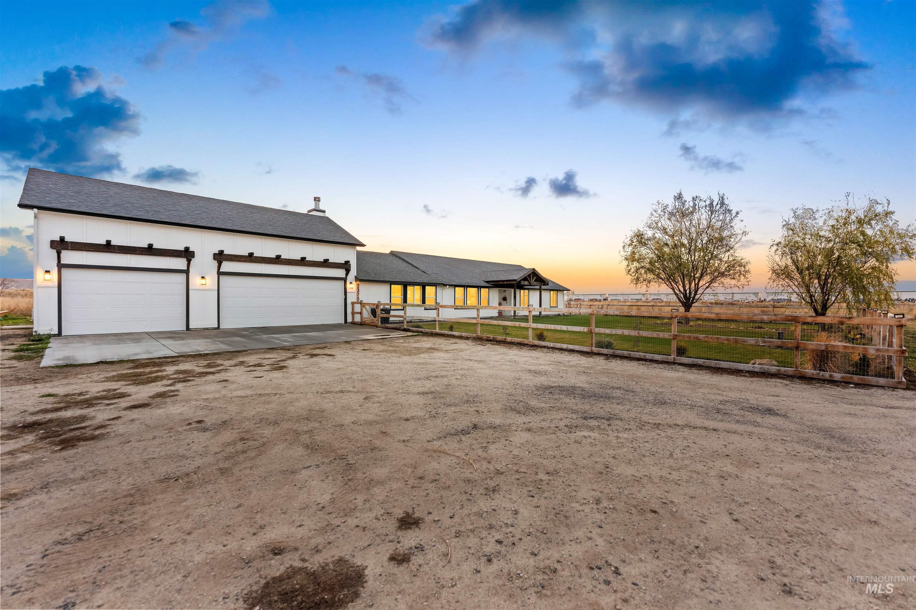 View of front of property with dirt driveway, roof with shingles, a garage, and stucco siding