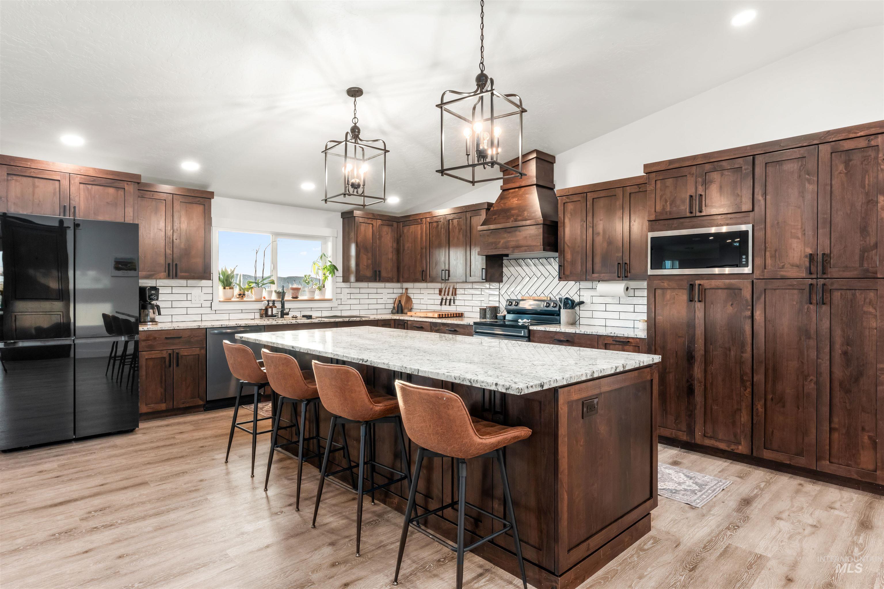 Kitchen featuring appliances with stainless steel finishes, a center island, hanging light fixtures, vaulted ceiling, and recessed lighting