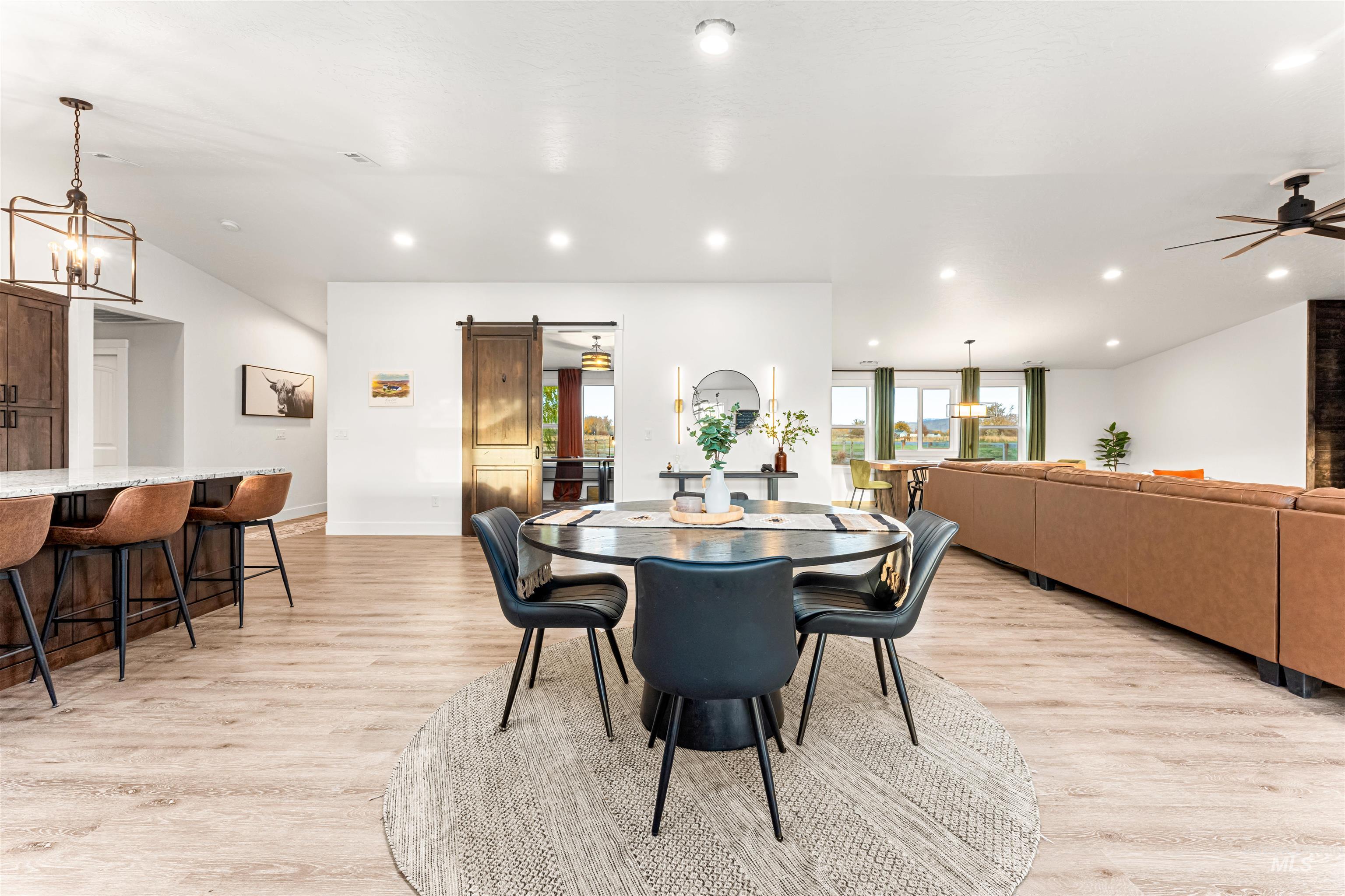 Dining area with a barn door, a chandelier, light wood finished floors, and recessed lighting