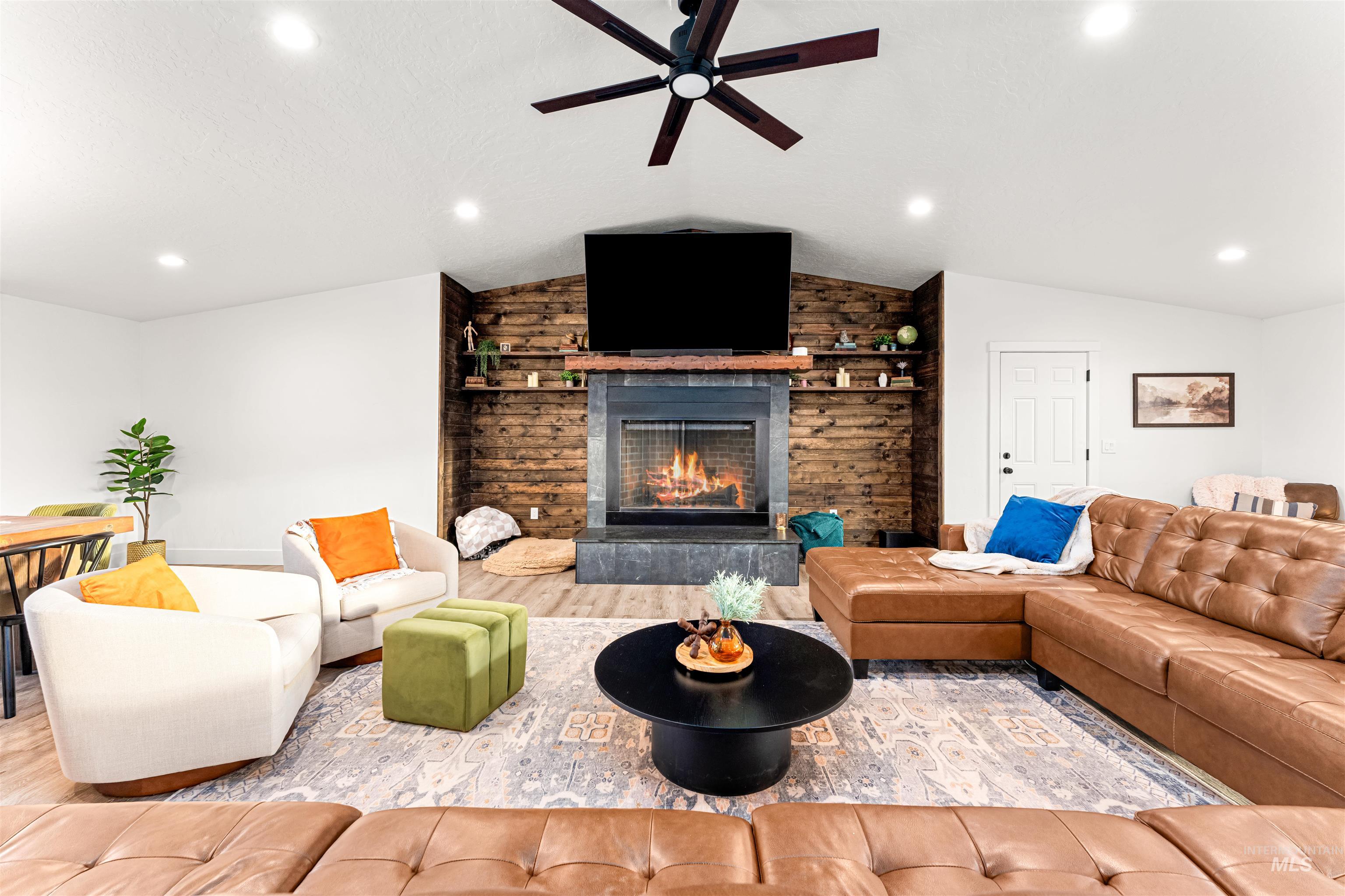 Living area featuring a stone fireplace, recessed lighting, lofted ceiling, wood finished floors, and a ceiling fan