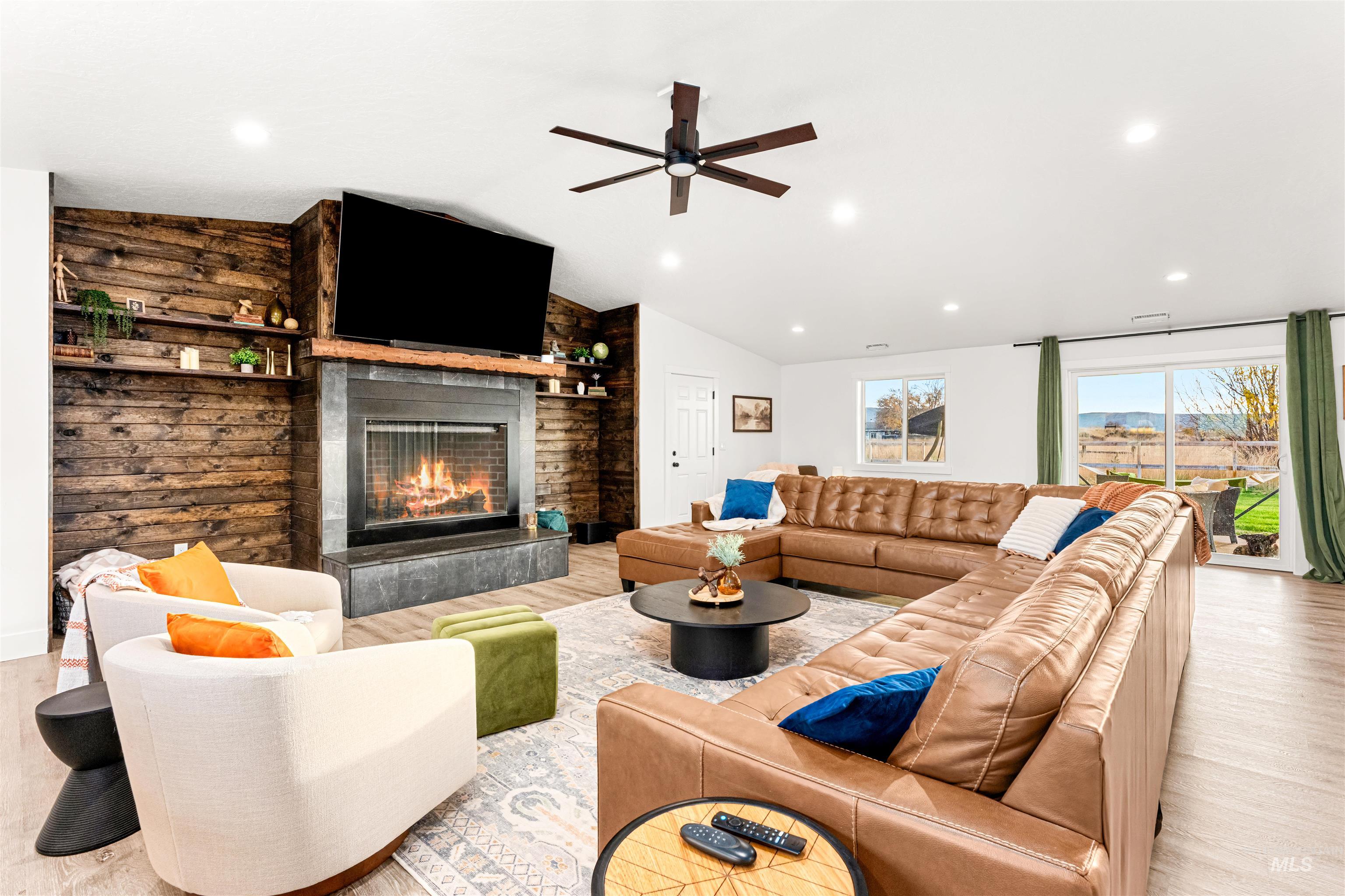 Living area with lofted ceiling, a fireplace, recessed lighting, wood finished floors, and a ceiling fan