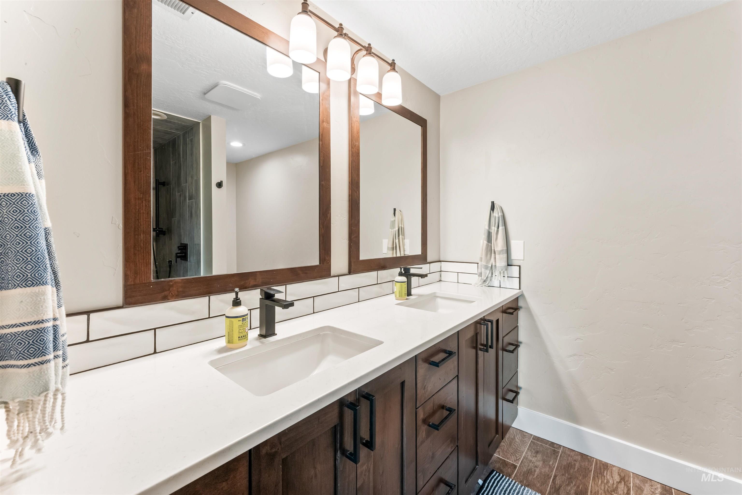 Full bath with double vanity, wood tiled floors, and backsplash