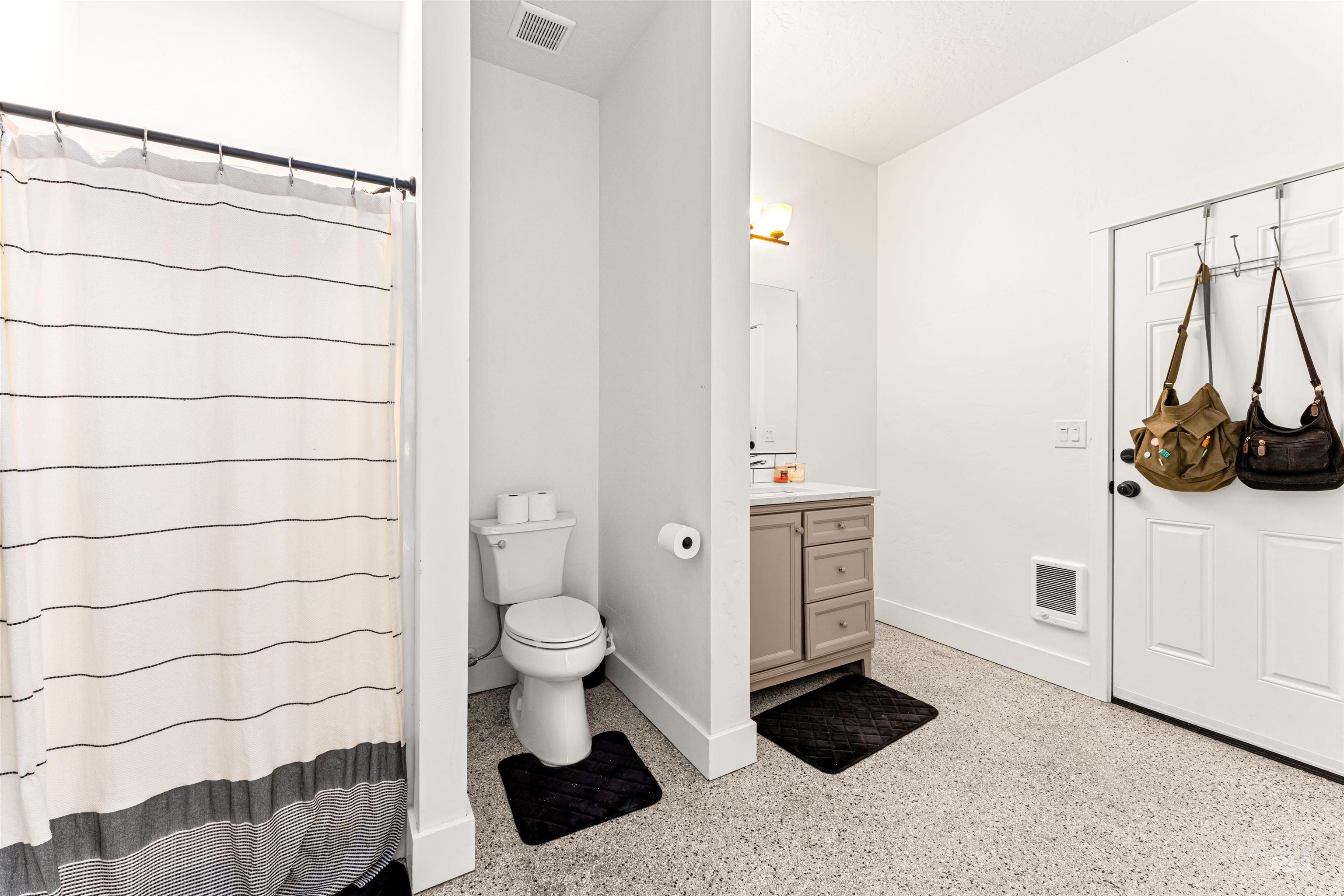 Bathroom featuring vanity, dark speckled floor, and a shower with shower curtain