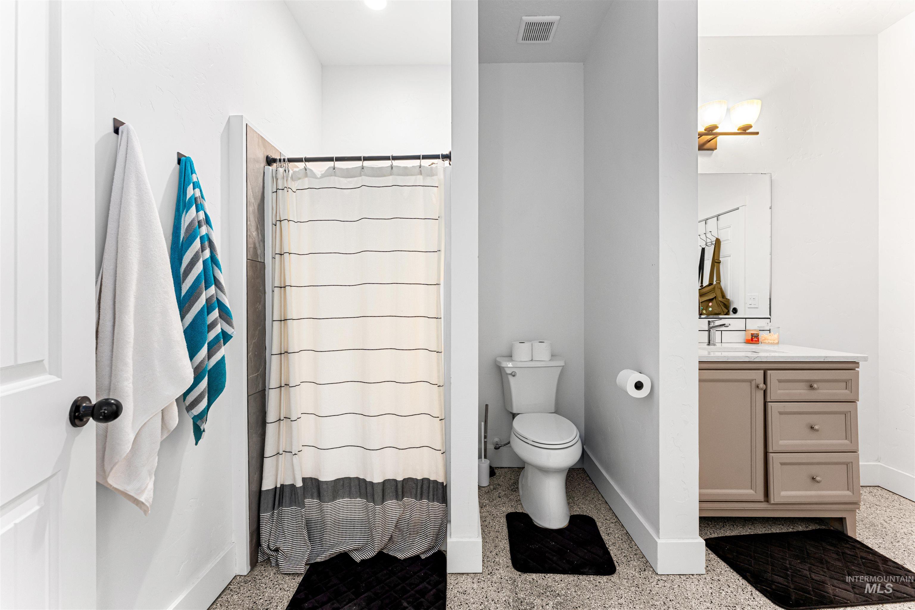 Bathroom featuring vanity, dark aggregate flooring, and a shower with curtain
