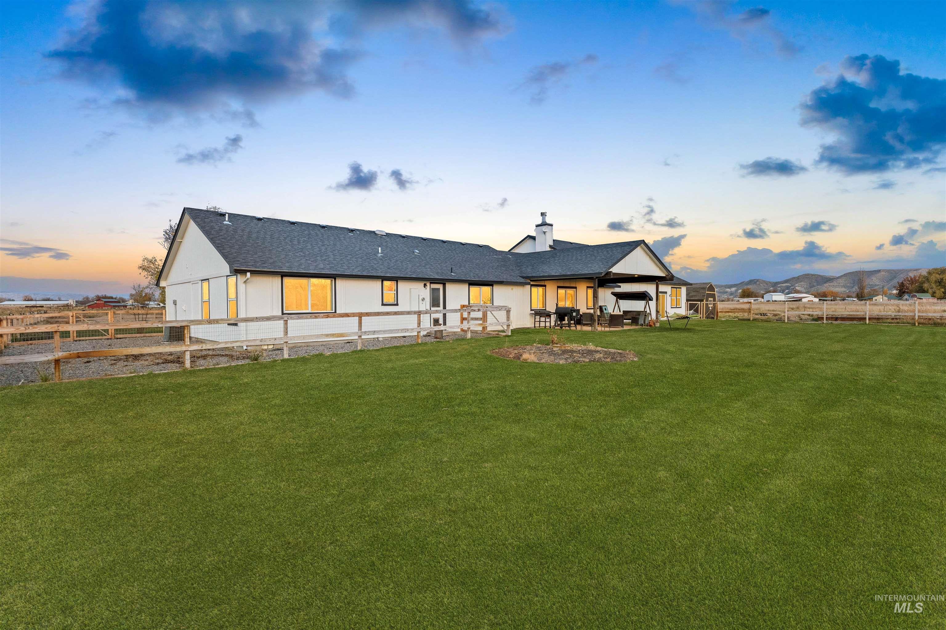 Back of property at dusk featuring a fenced backyard, a patio area, a chimney, and roof with shingles
