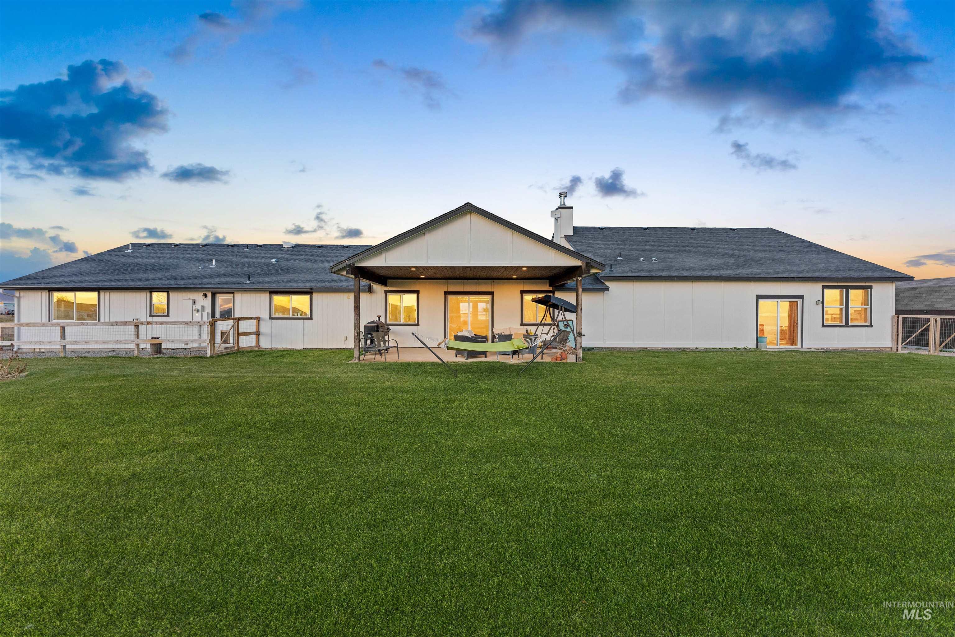 Back of house with a patio, a yard, a chimney, and a shingled roof