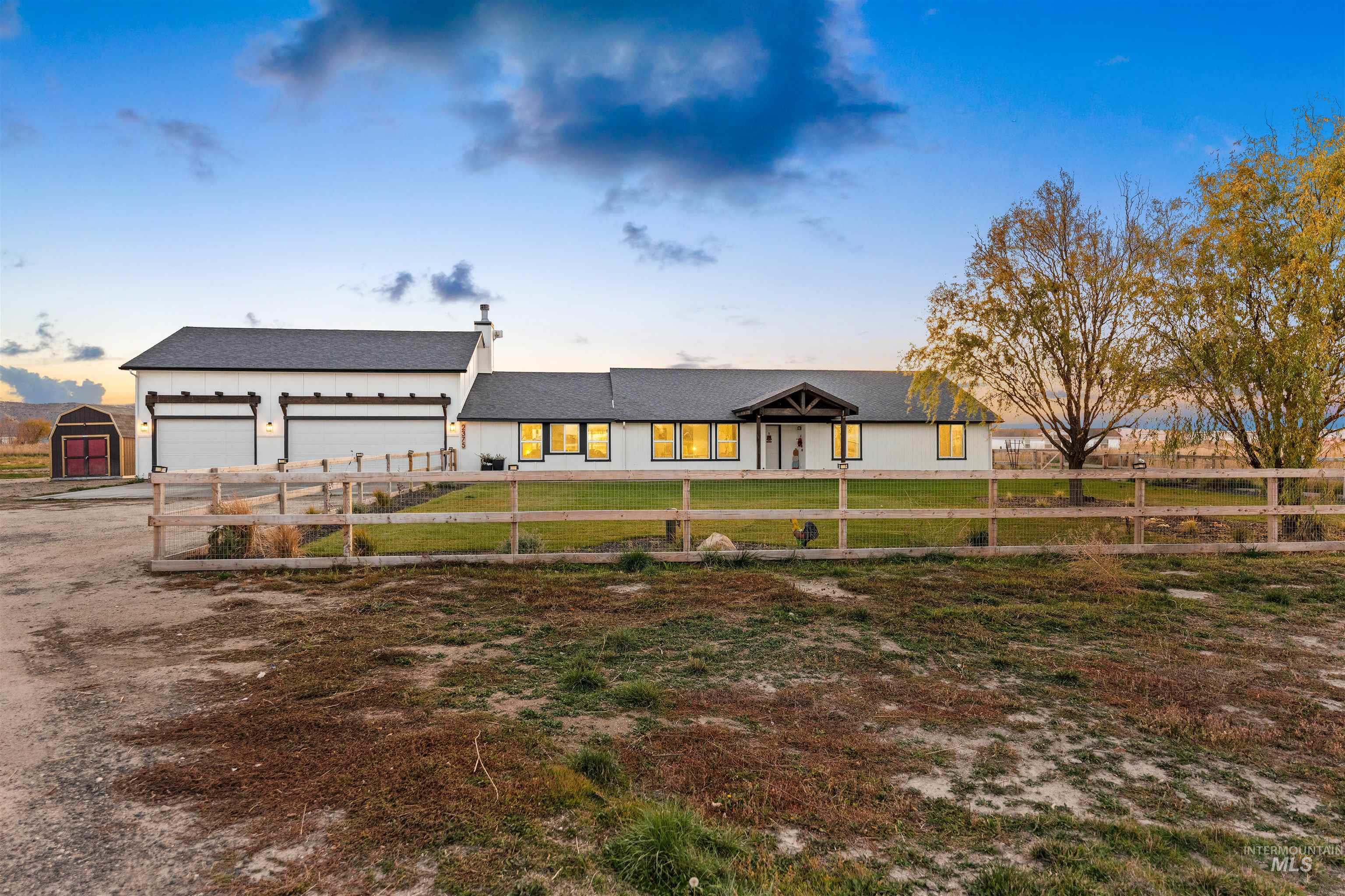 View of front facade with driveway, a fenced front yard, a chimney, and a garage