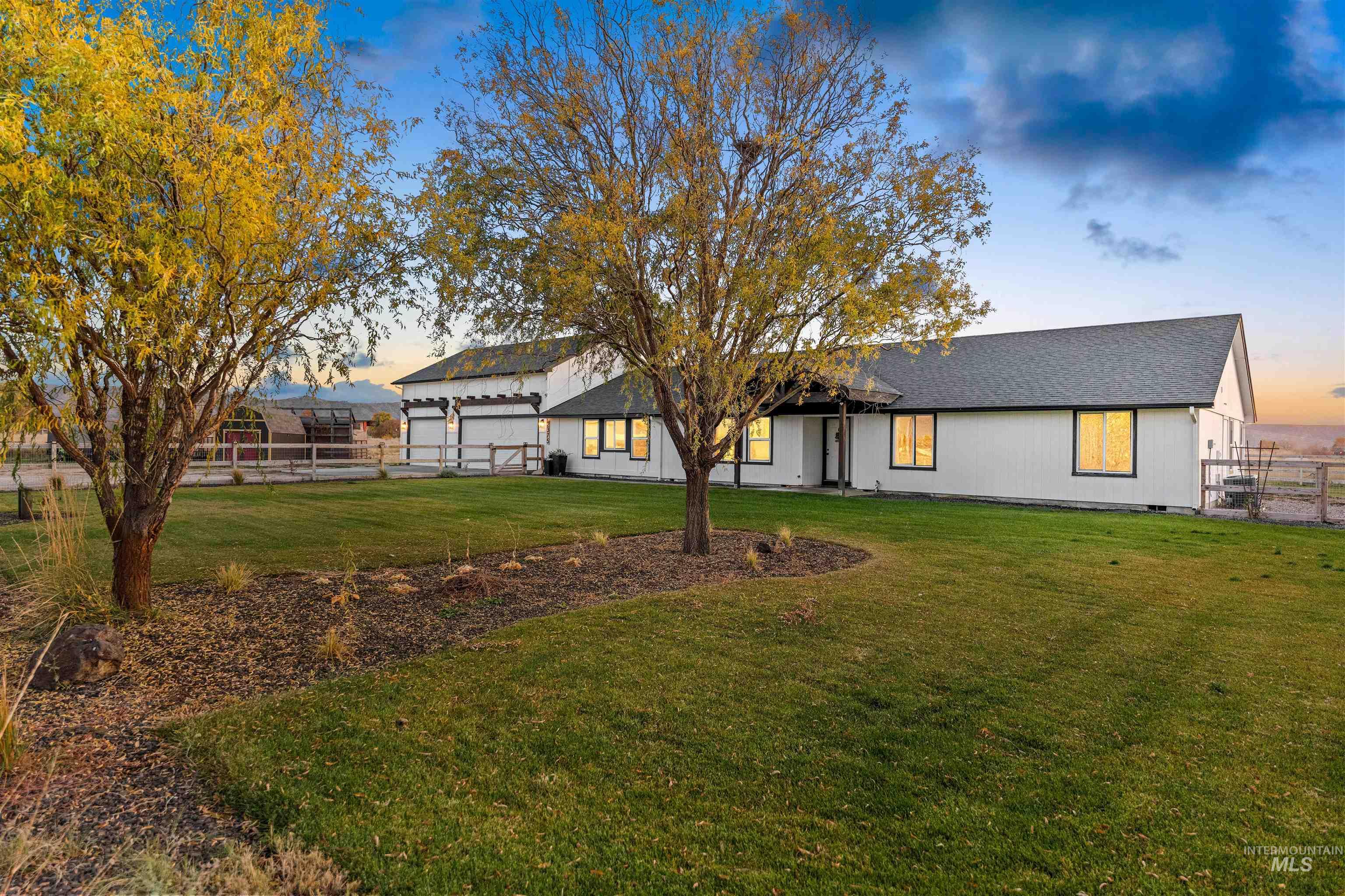 View of front of home featuring a shingled roof, a garage, and a patio area