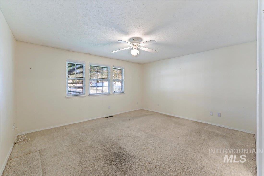 Spare room featuring light colored carpet, a textured ceiling, and ceiling fan