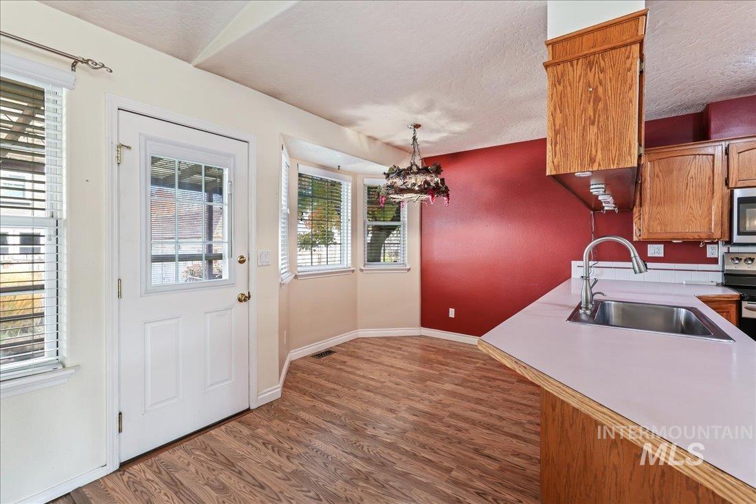 Kitchen featuring light countertops, dark wood-type flooring, stainless steel appliances, a textured ceiling, and brown cabinetry