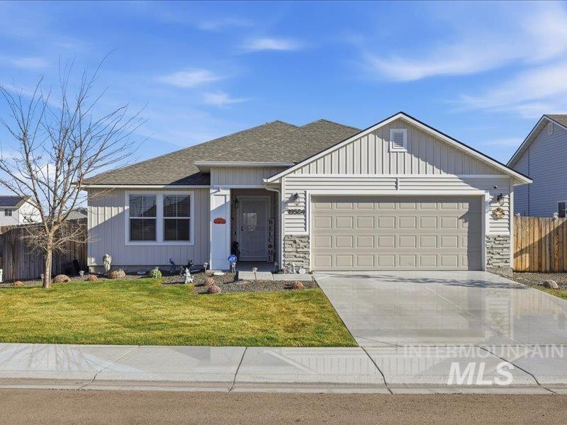Single story home featuring driveway, a garage, a shingled roof, and board and batten siding