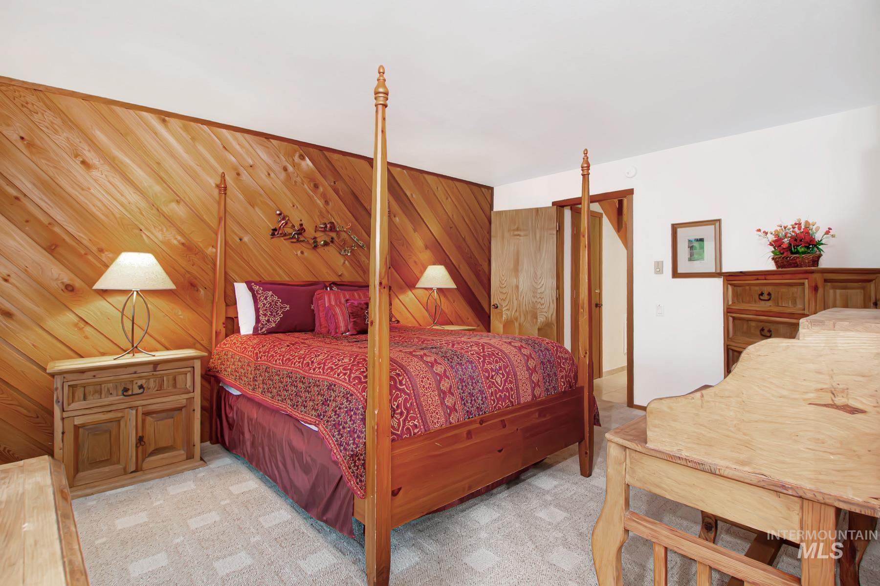 Bedroom with wooden walls and light carpet