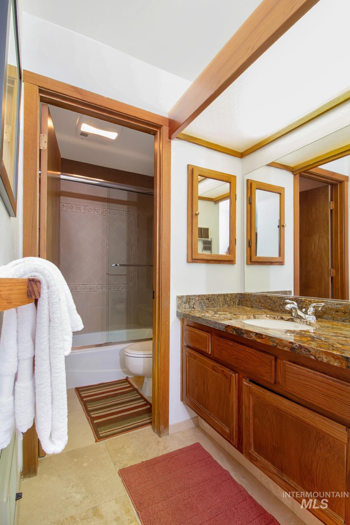 Full bathroom with vanity and bath / shower combo with glass door