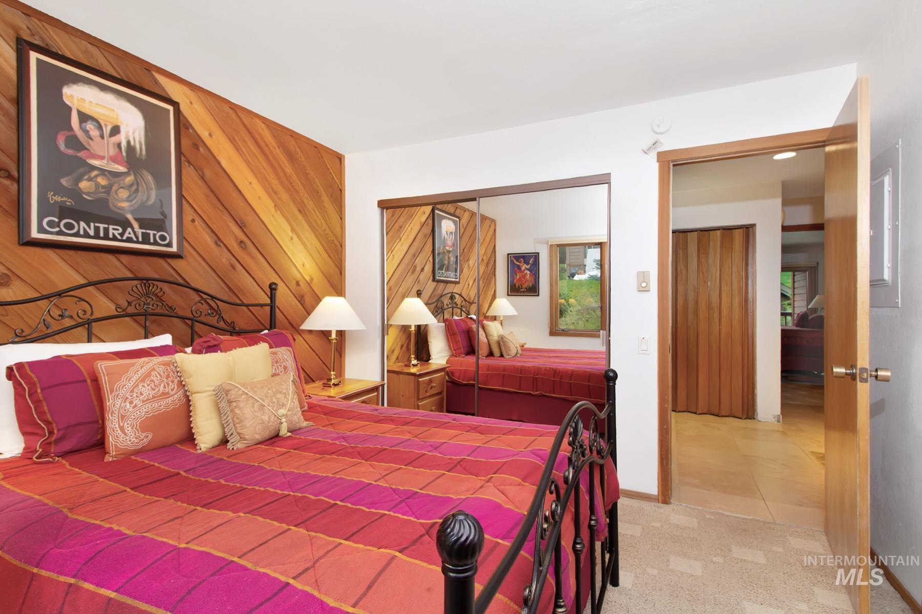 Carpeted bedroom featuring a closet, wood walls, and tile patterned flooring