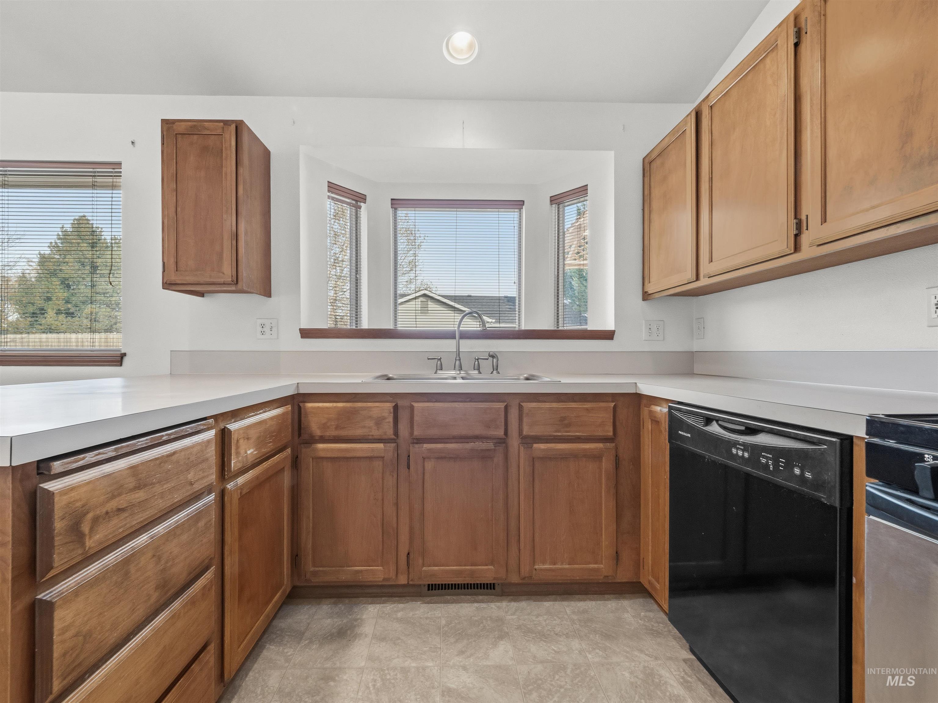 Kitchen with dishwasher, light countertops, brown cabinetry, a peninsula, and recessed lighting