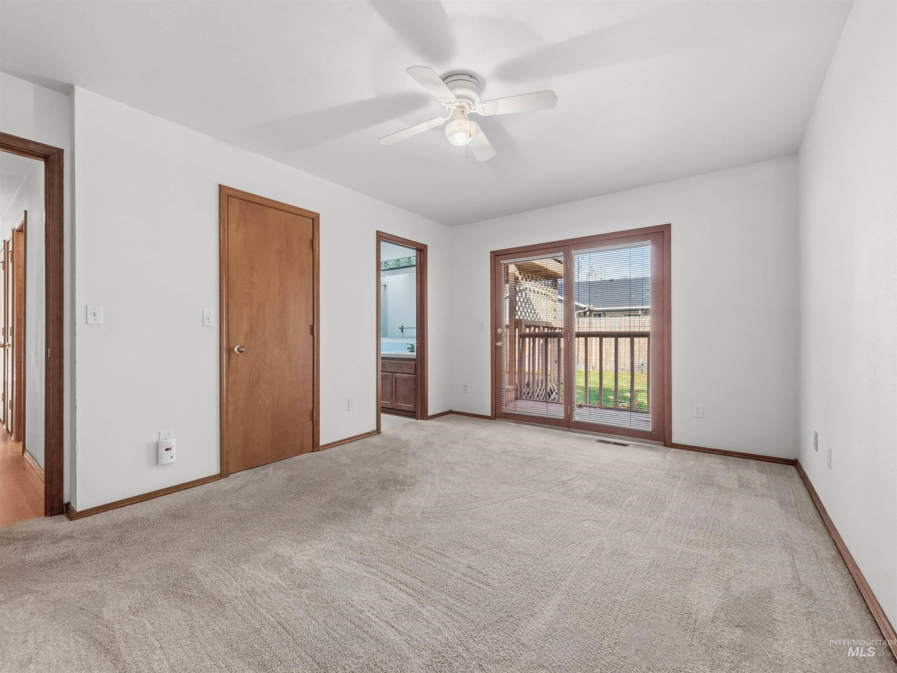 Unfurnished bedroom featuring connected bathroom, light colored carpet, a ceiling fan, and access to exterior