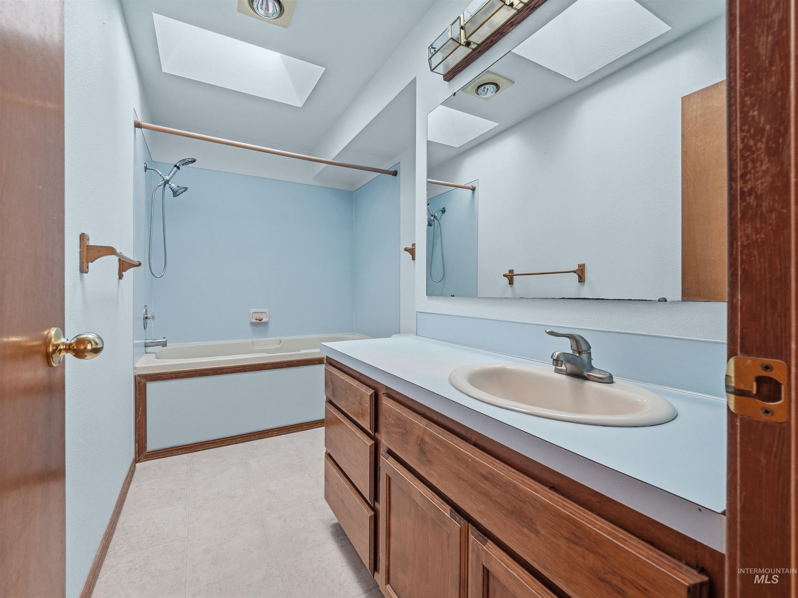 Bathroom with a skylight, bathtub / shower combination, and vanity