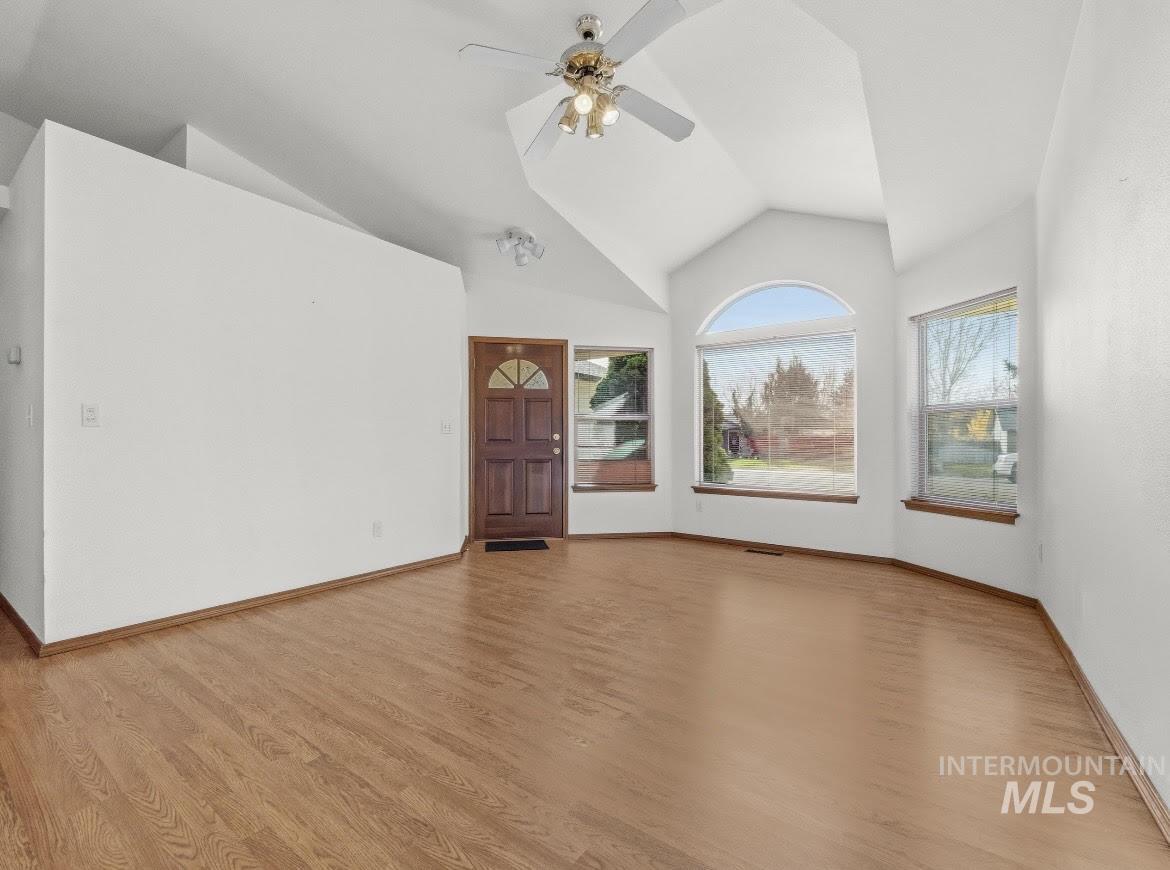 Unfurnished living room featuring a ceiling fan, light wood-type flooring, and high vaulted ceiling