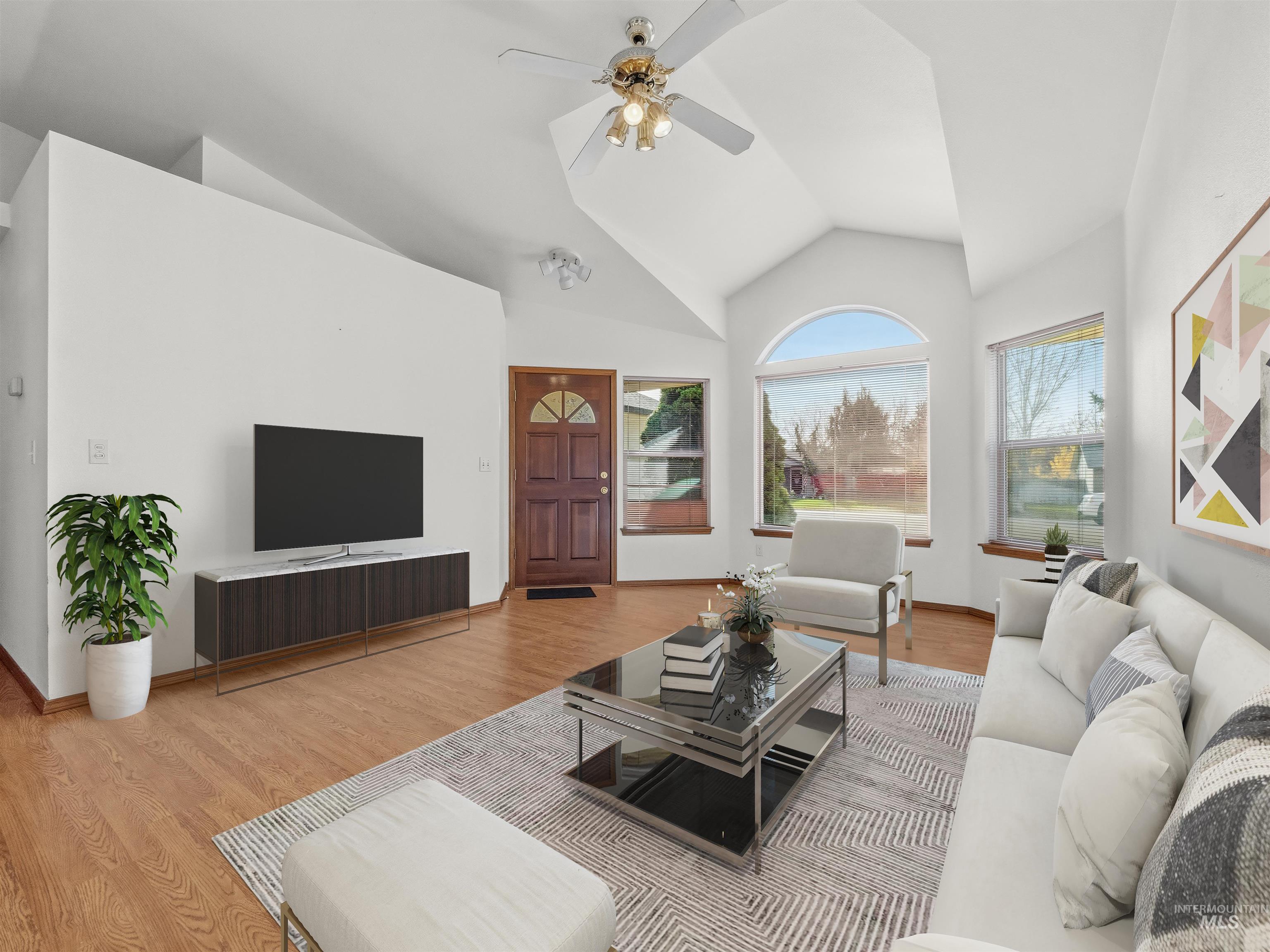 Living room with wood finished floors, ceiling fan, and high vaulted ceiling