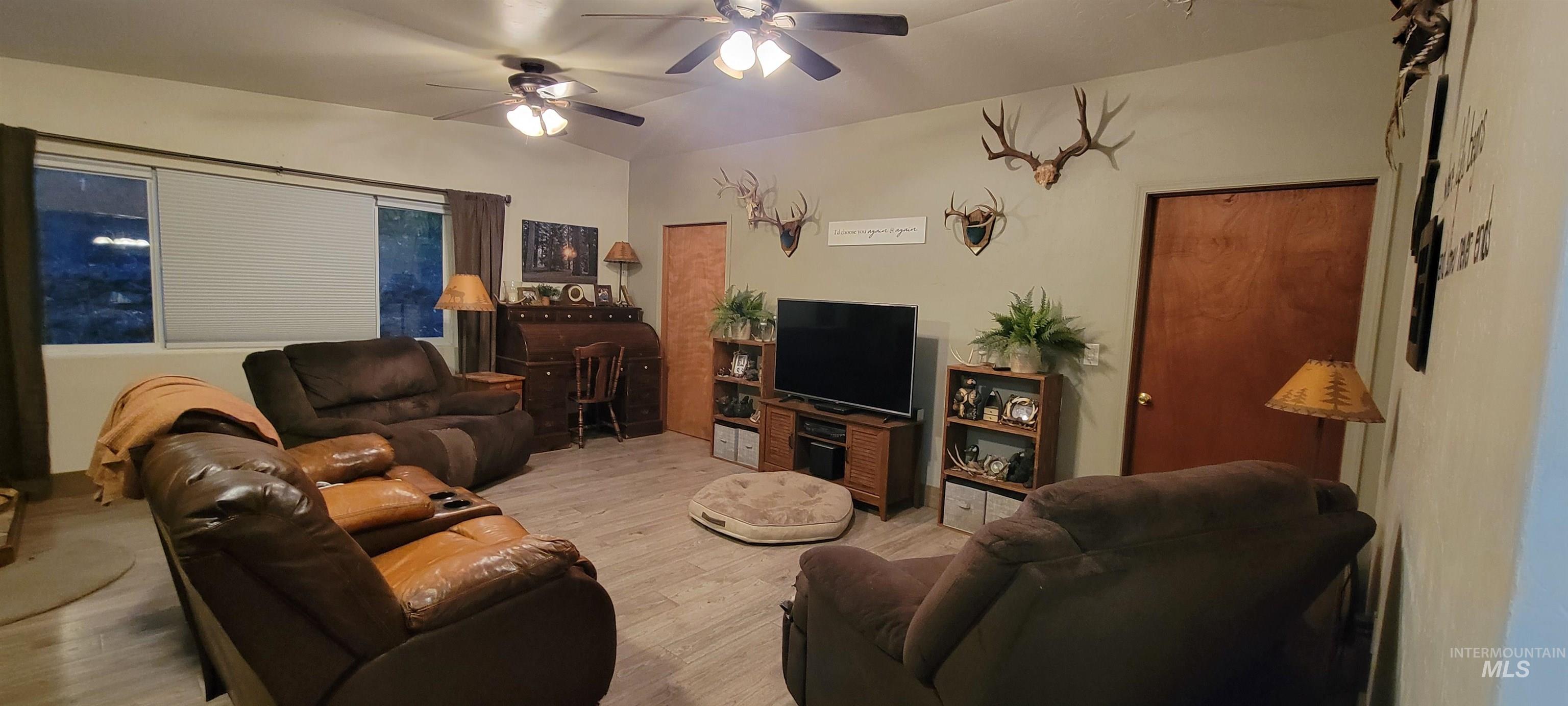 Living area featuring wood finished floors, a ceiling fan, and lofted ceiling