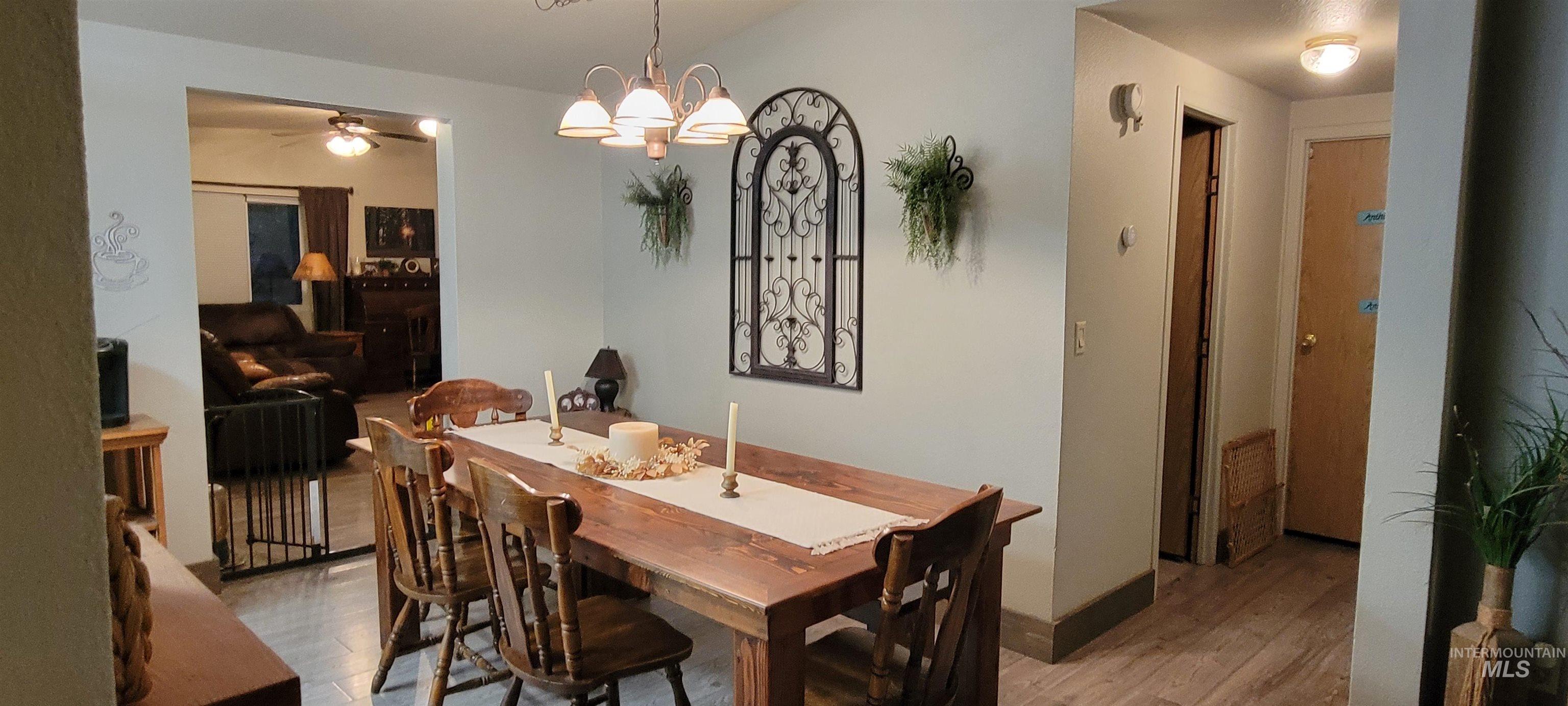 Dining area featuring light wood-type flooring, a chandelier, and a ceiling fan
