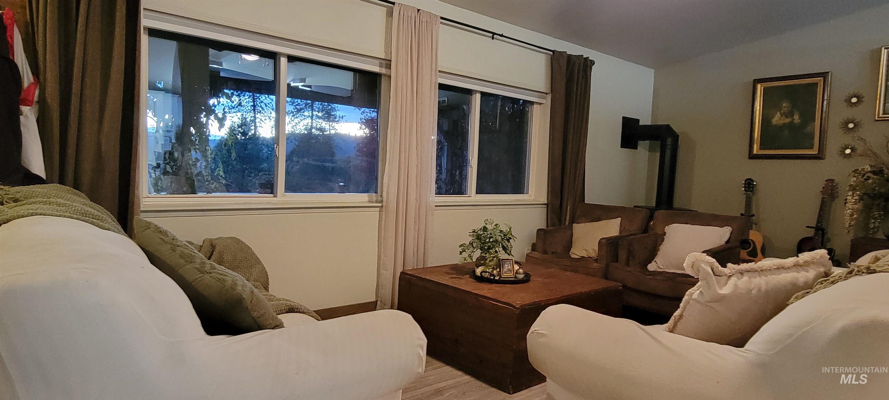 Living room featuring a wood stove, vaulted ceiling, and wood finished floors