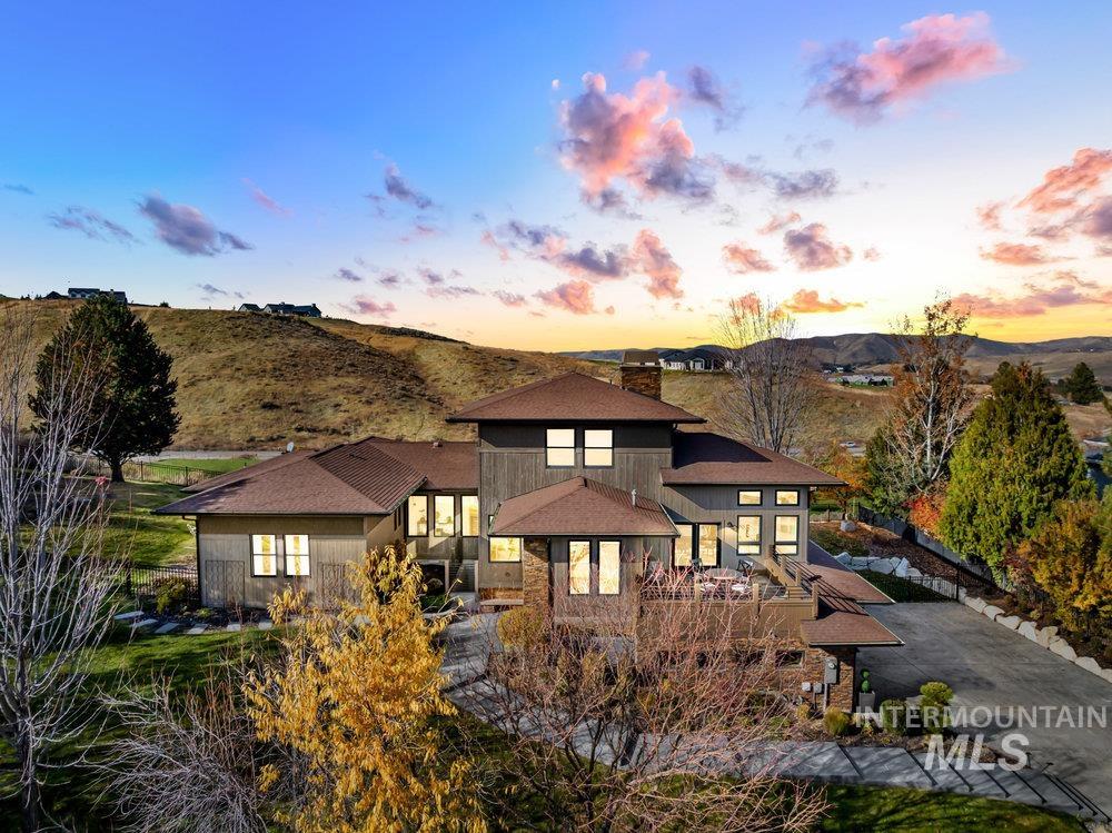 Rear view of property with a chimney, a shingled roof, stone siding, and a mountain view