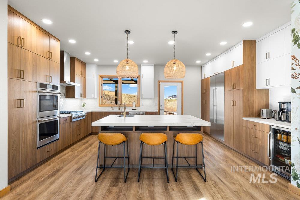 Kitchen featuring brown cabinetry, a breakfast bar area, tasteful backsplash, hanging light fixtures, and recessed lighting