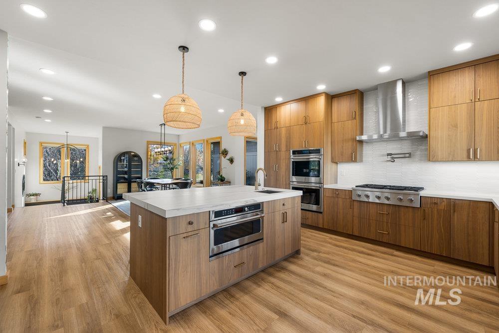Kitchen featuring recessed lighting, backsplash, modern cabinets, pendant lighting, and light wood finished floors