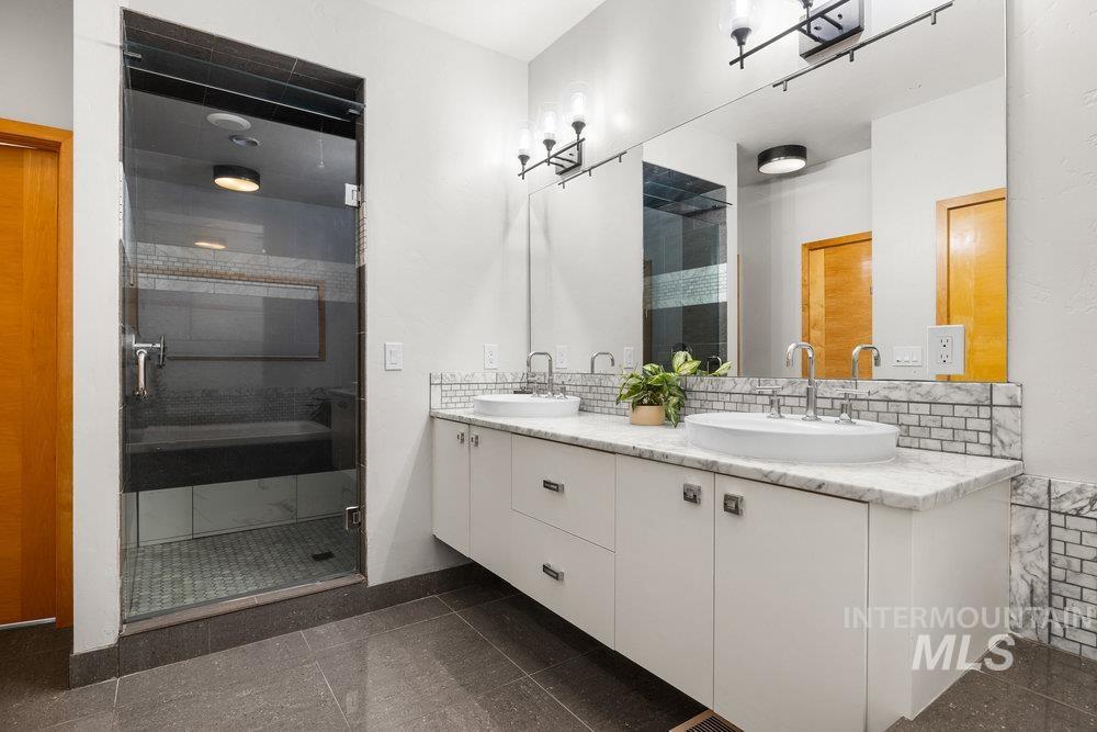 Bathroom featuring double vanity, a stall shower, and granite floors