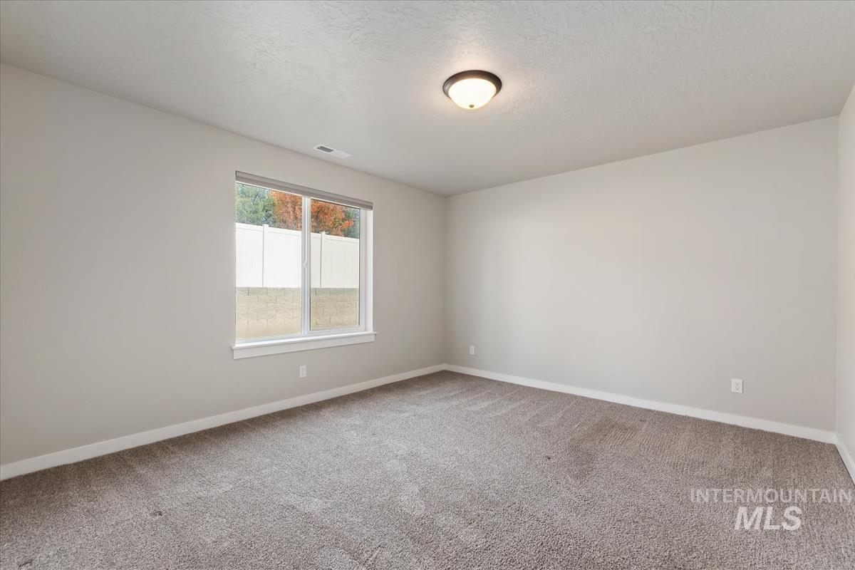 Unfurnished room with light colored carpet and a textured ceiling