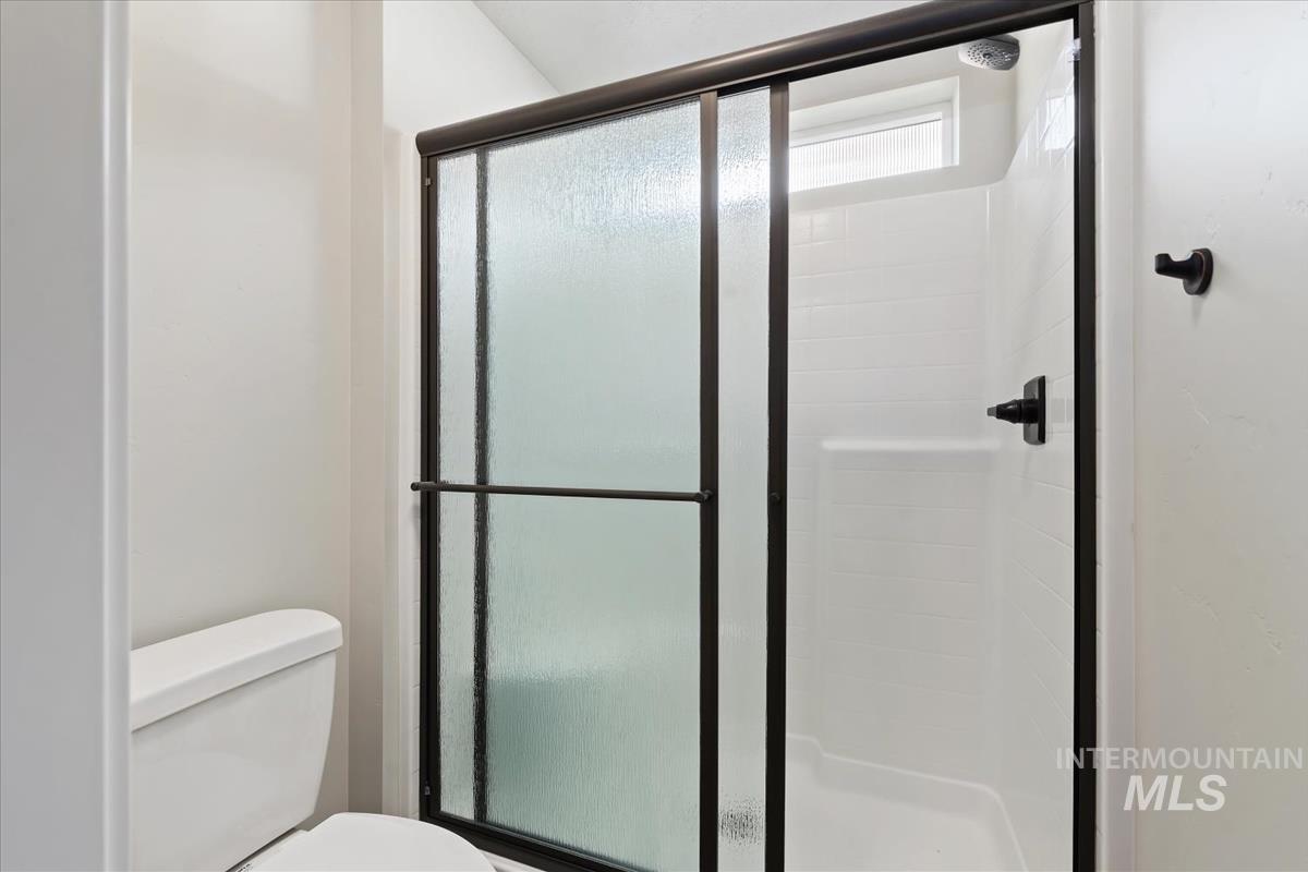 Full bathroom featuring a stall shower and toilet
