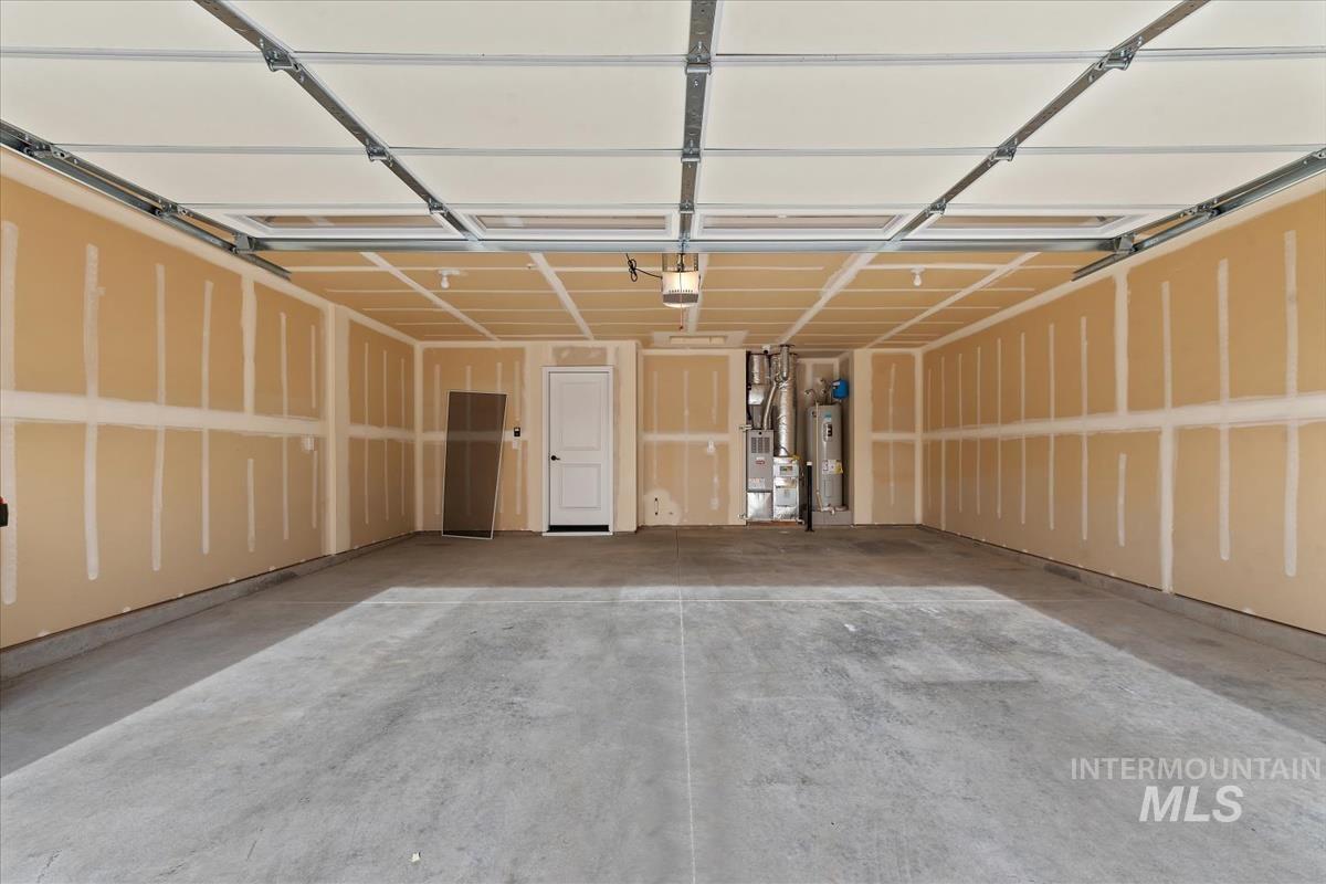 Garage featuring water heater, heating unit, and a garage door opener