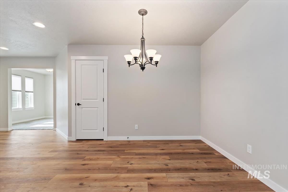 Unfurnished dining area featuring a chandelier, wood finished floors, and recessed lighting