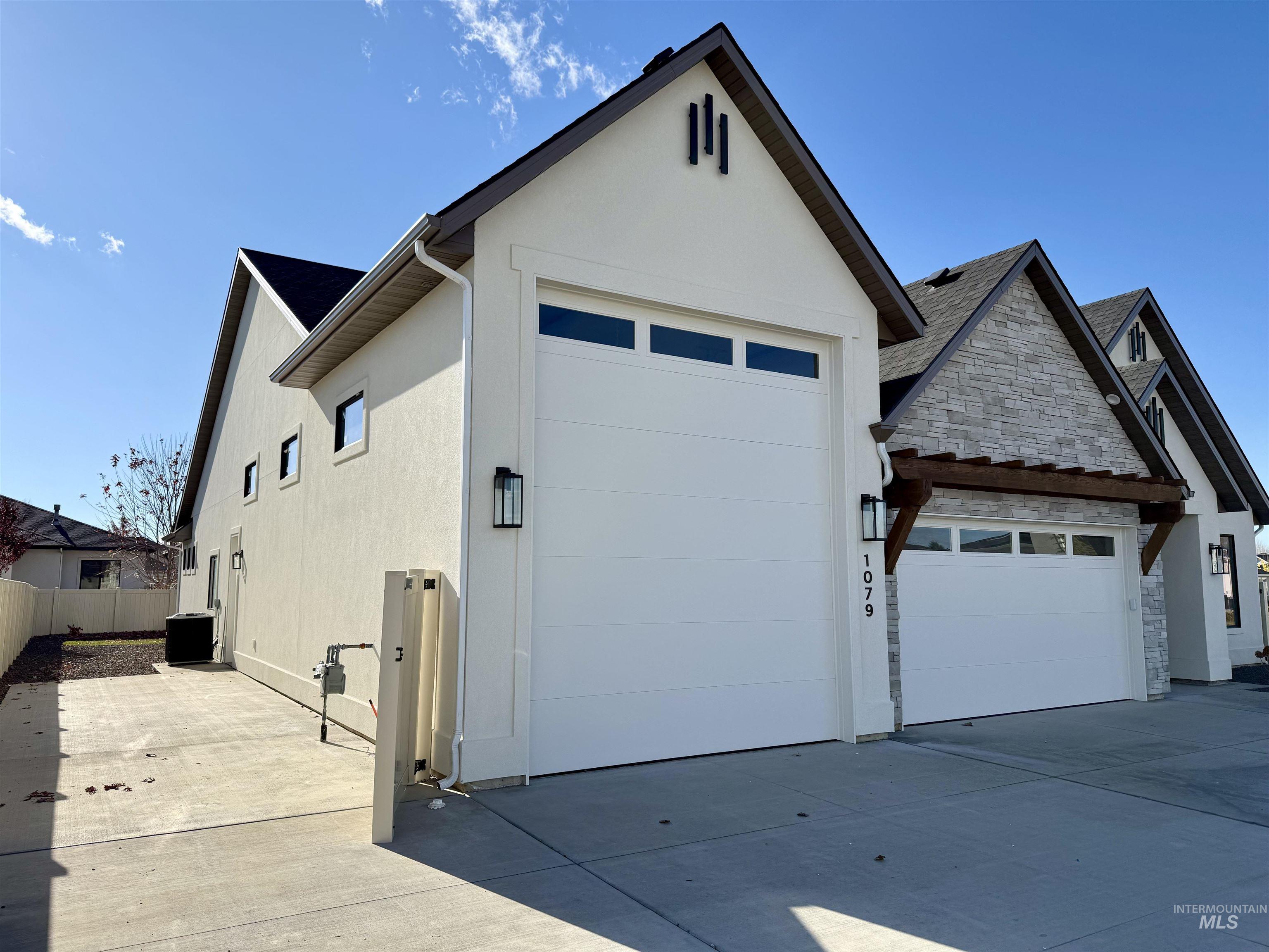 View of front of property featuring stone siding, driveway, stucco siding, and an attached garage