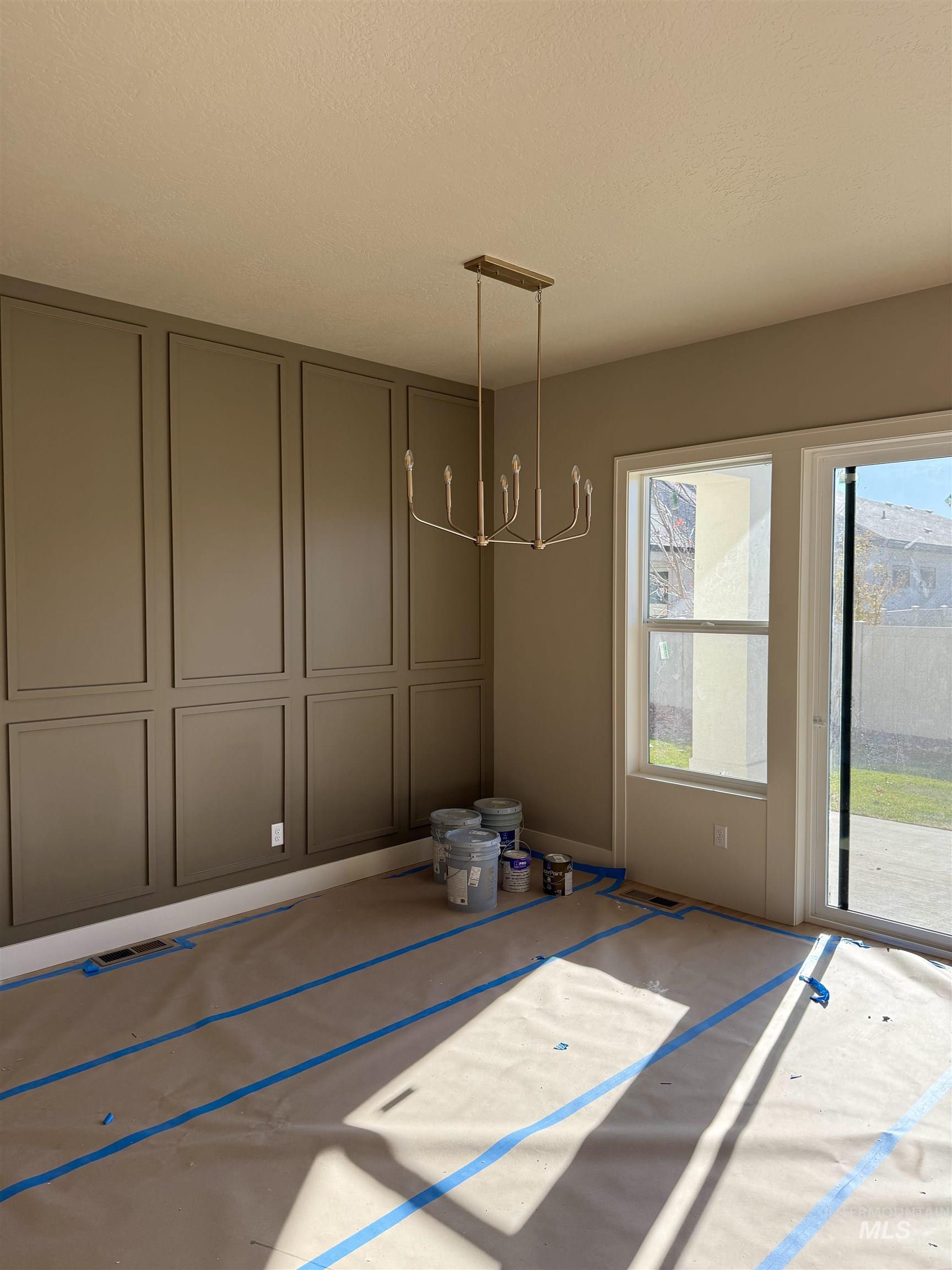 Unfurnished dining area with a chandelier, a decorative wall, and a textured ceiling