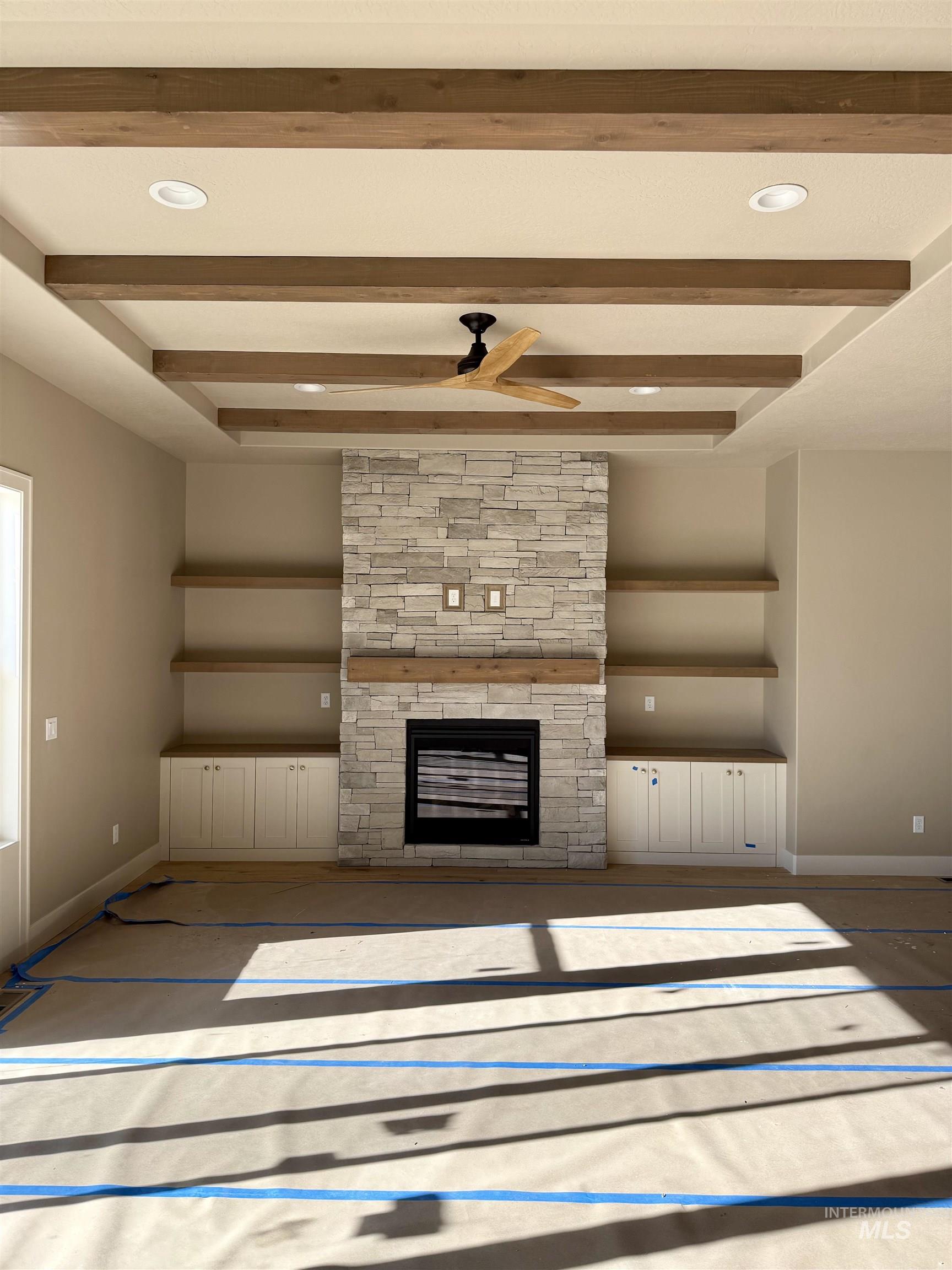 Unfurnished living room featuring beamed ceiling, a stone fireplace, a ceiling fan, and recessed lighting