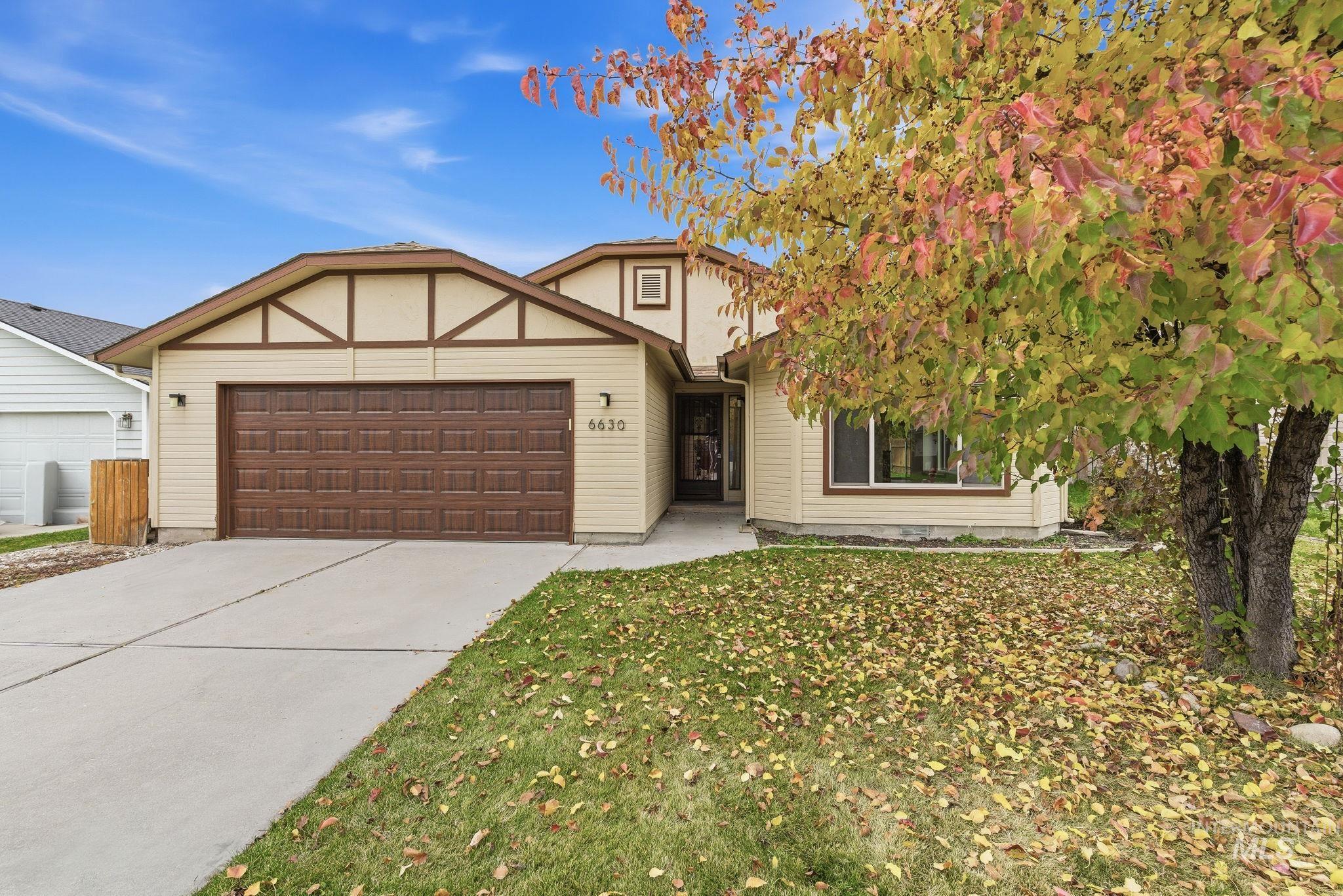 View of front of property featuring a garage, driveway, and a front yard