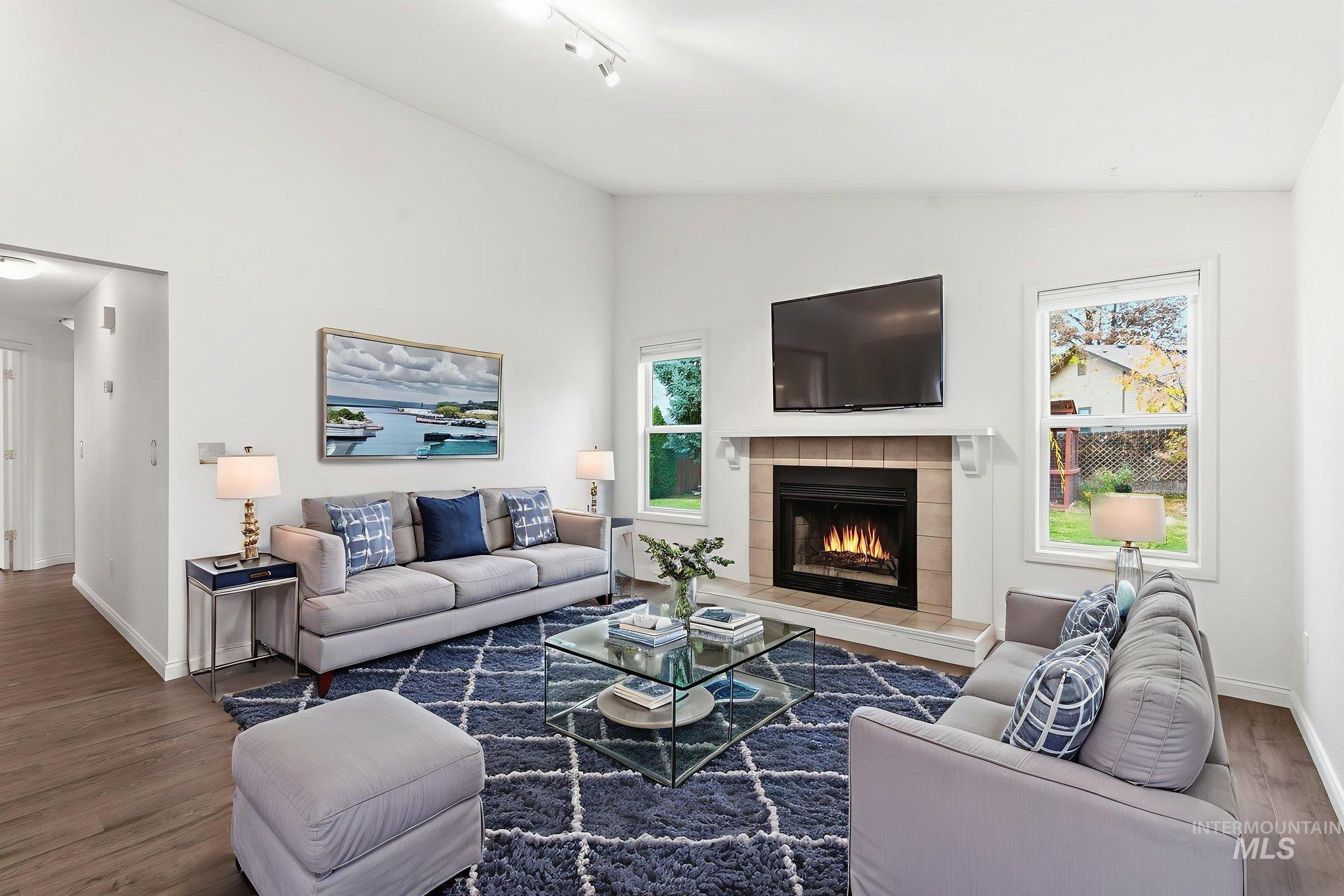 Virtually staged family room with wood finished floors, a fireplace, and high vaulted ceiling