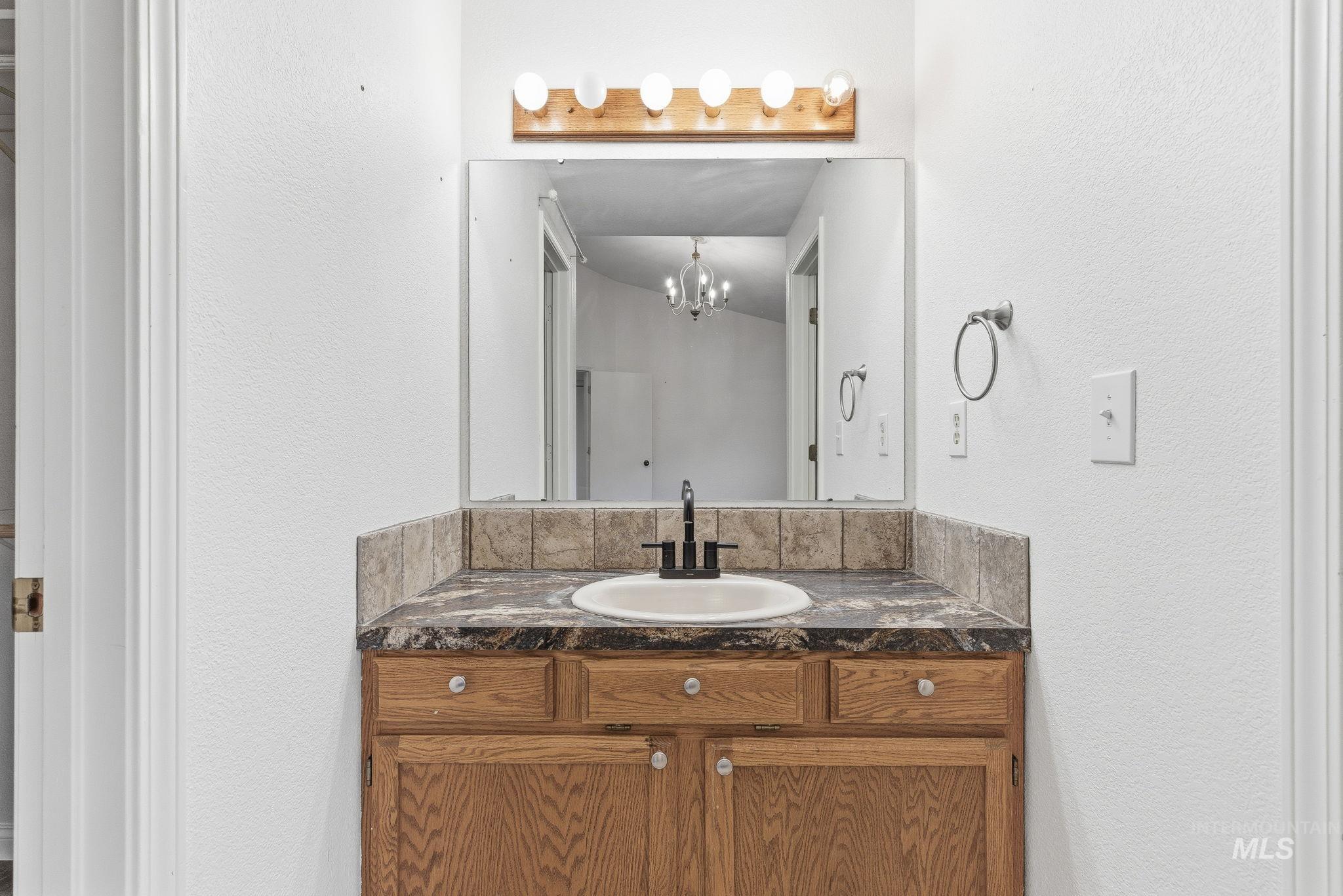 Bathroom with a textured wall, vanity, and a chandelier