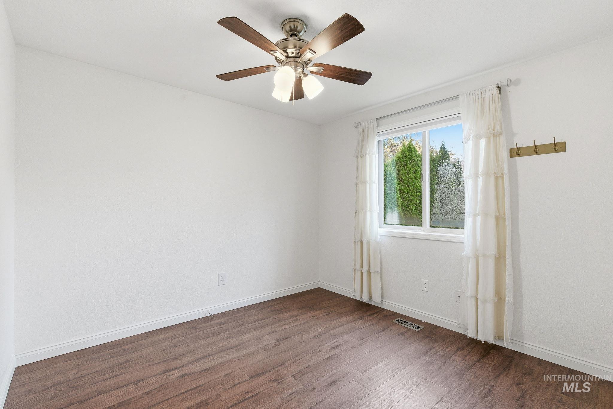 Empty room with dark wood finished floors and a ceiling fan