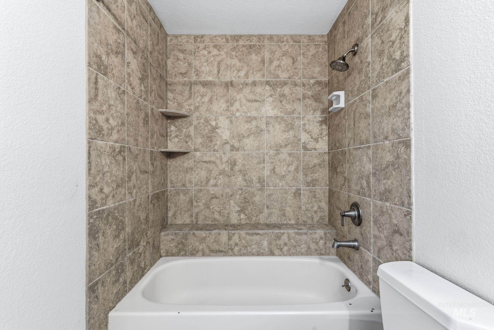 Full bathroom featuring a textured wall and tub / shower combination