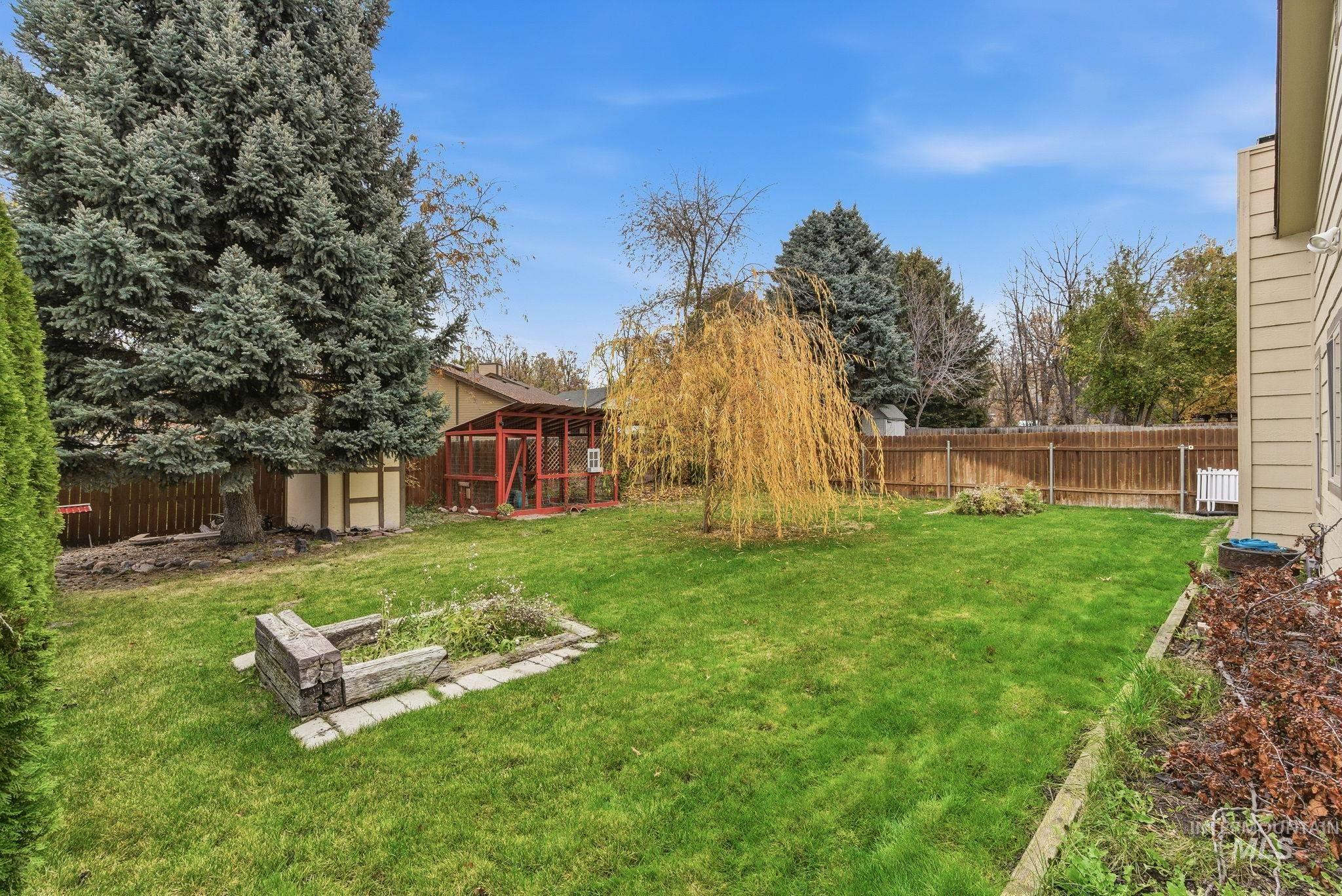 Fenced backyard featuring an outbuilding and a vegetable garden